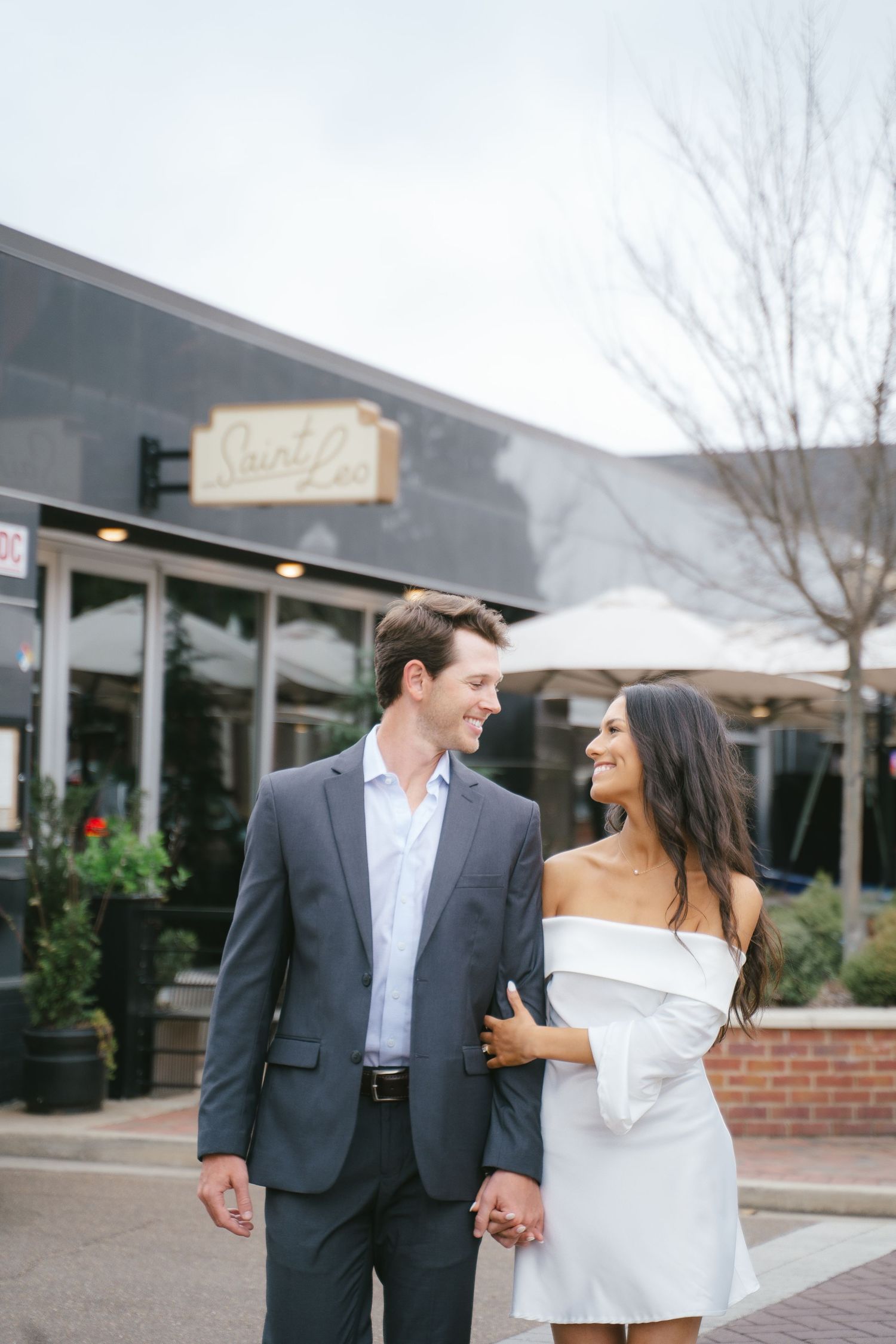 A couple strolls together through a shopping center courtyard on a cloudy day.