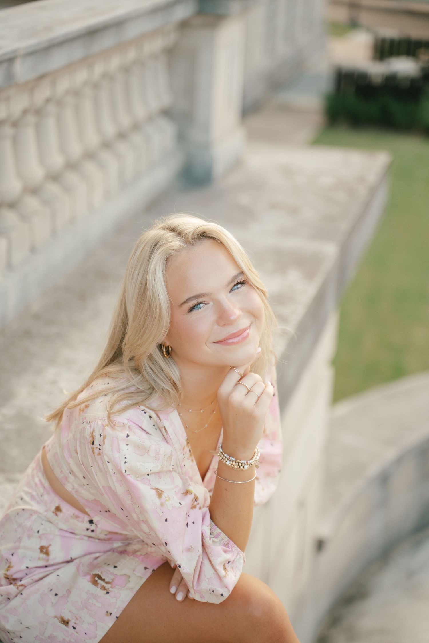 Dreamy portrait series in a pink floral dress against stone columns.