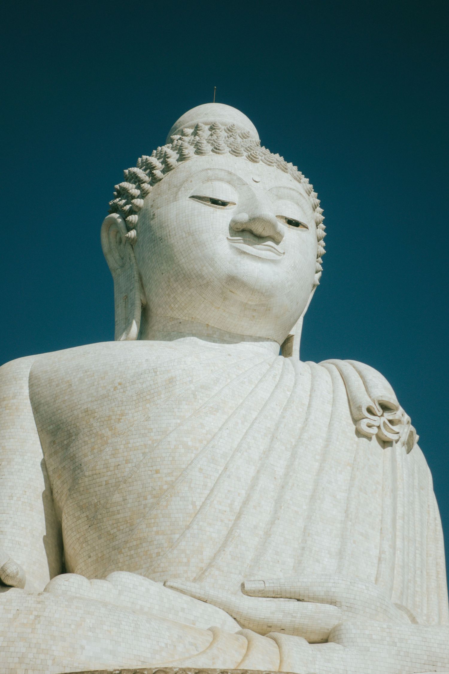 Large white marble Buddha statue shown in a series of close-up details highlighting its serene expression and reclining pose.