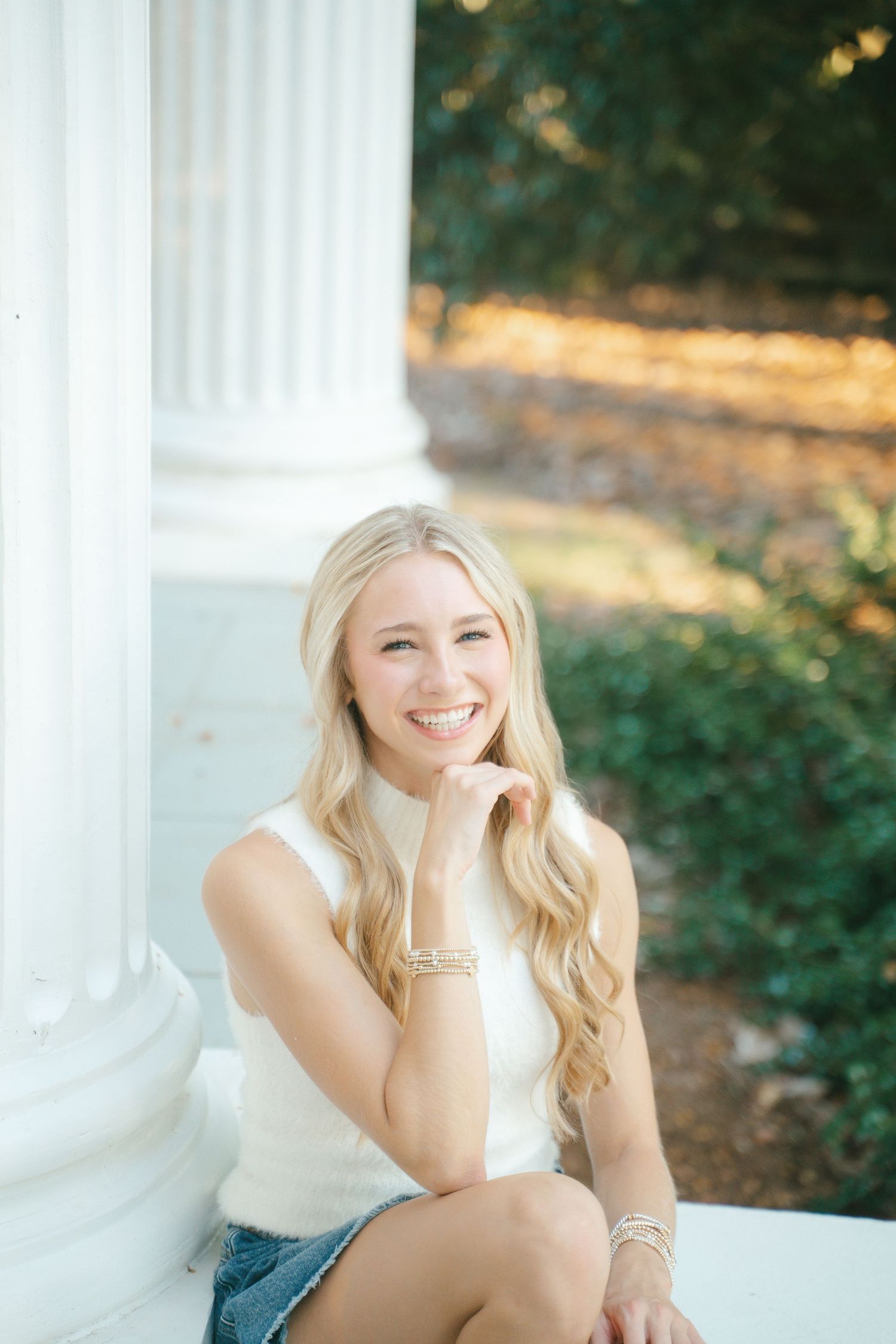 Bright outdoor portrait by white classical column in natural lighting.