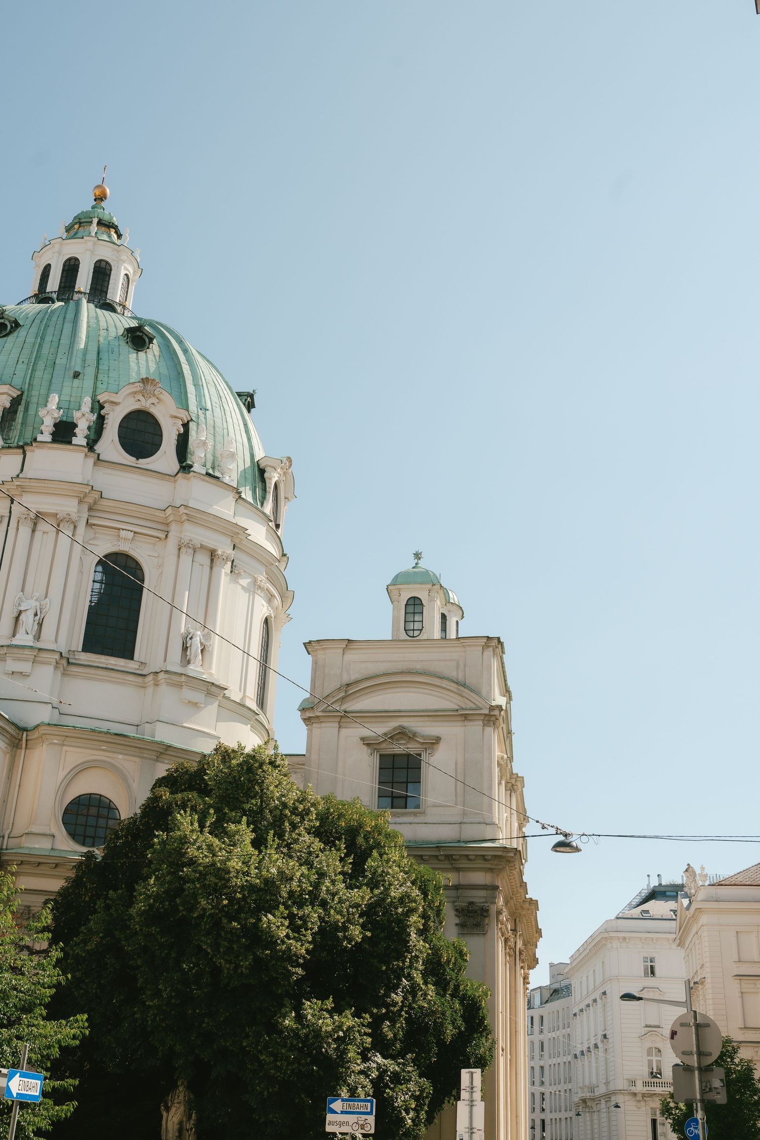Baroque church domes and spires against clear blue sky in Vienna's historic district.