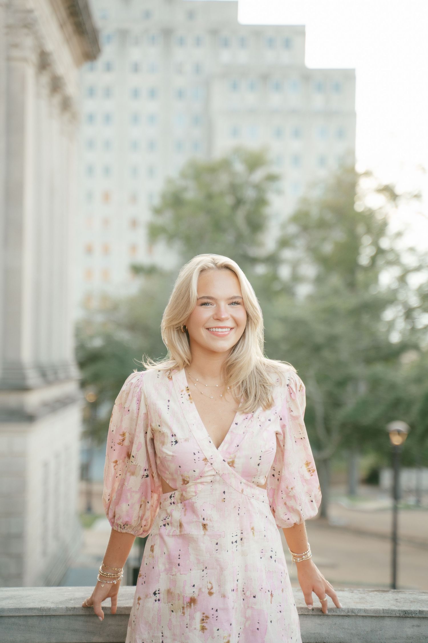 Candid moments captured in a romantic pink floral dress near classic architecture.