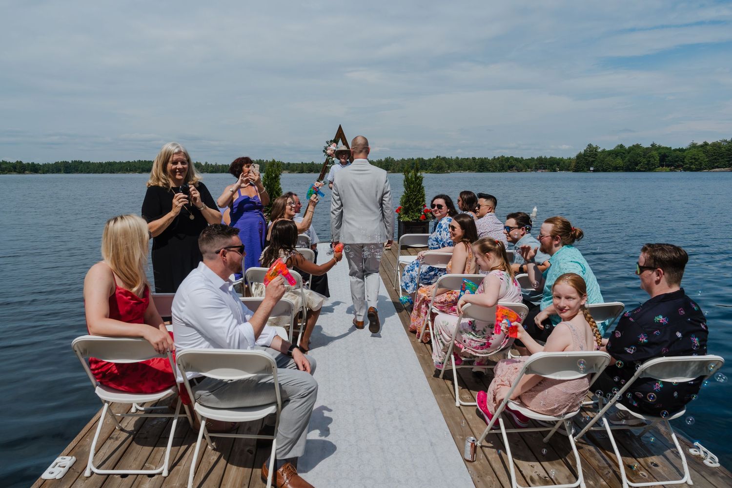 Group gathered on a pontoon boat for a celebration on a sunny day at the lake.