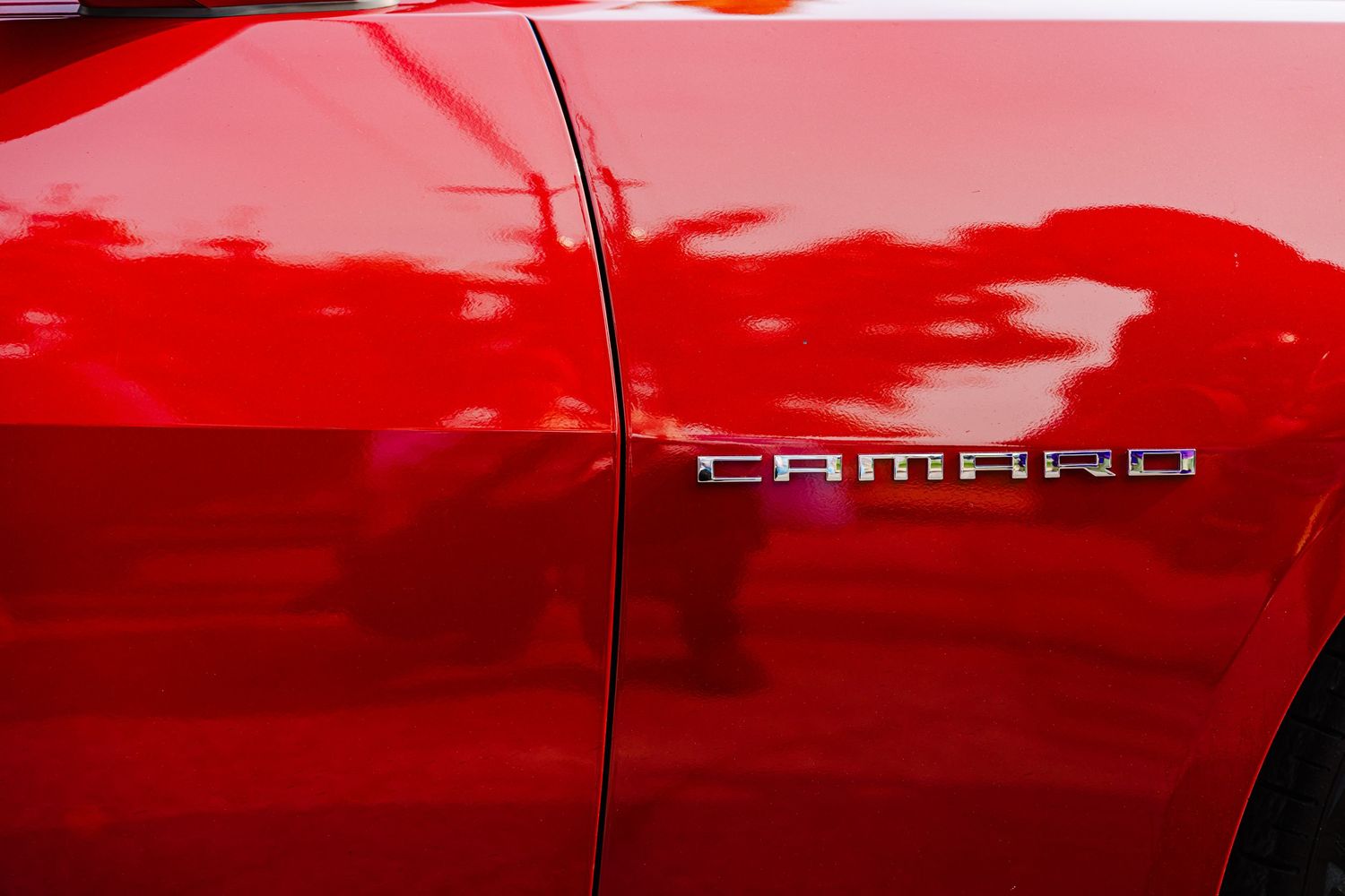 Close up detail shot of red Camaro car badge on glossy paint.