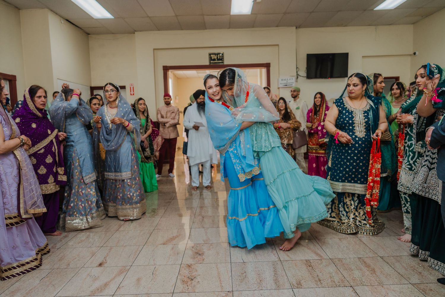 Guests in colorful traditional Indian attire dancing and celebrating during a wedding reception.