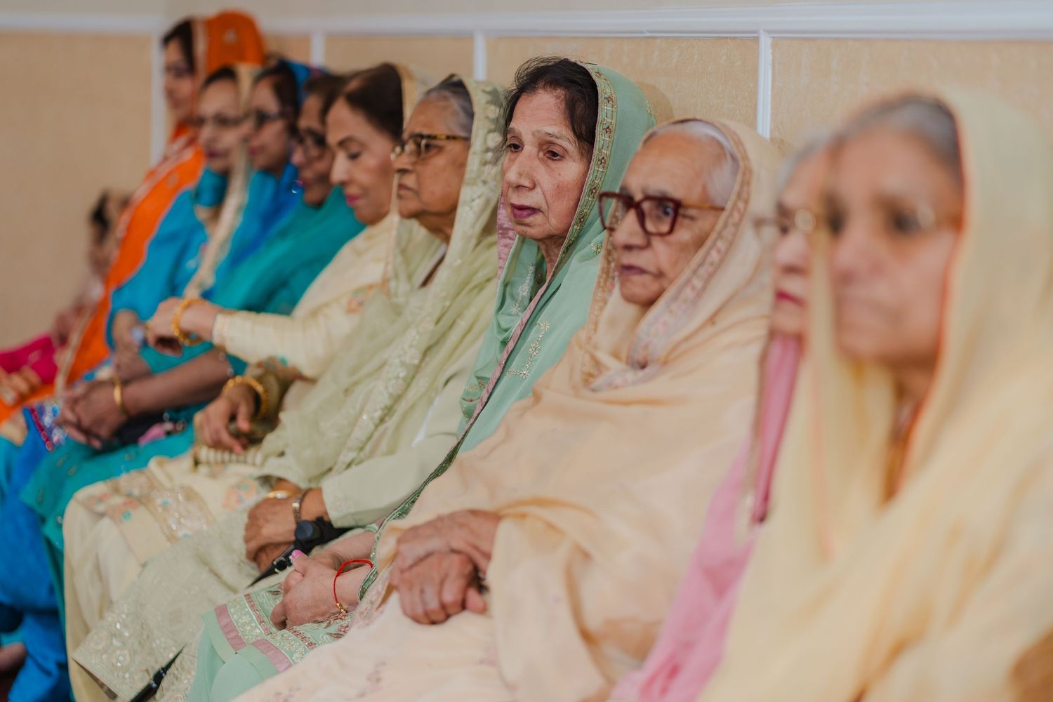 Group of women in traditional Indian attire seated together during a cultural ceremony.