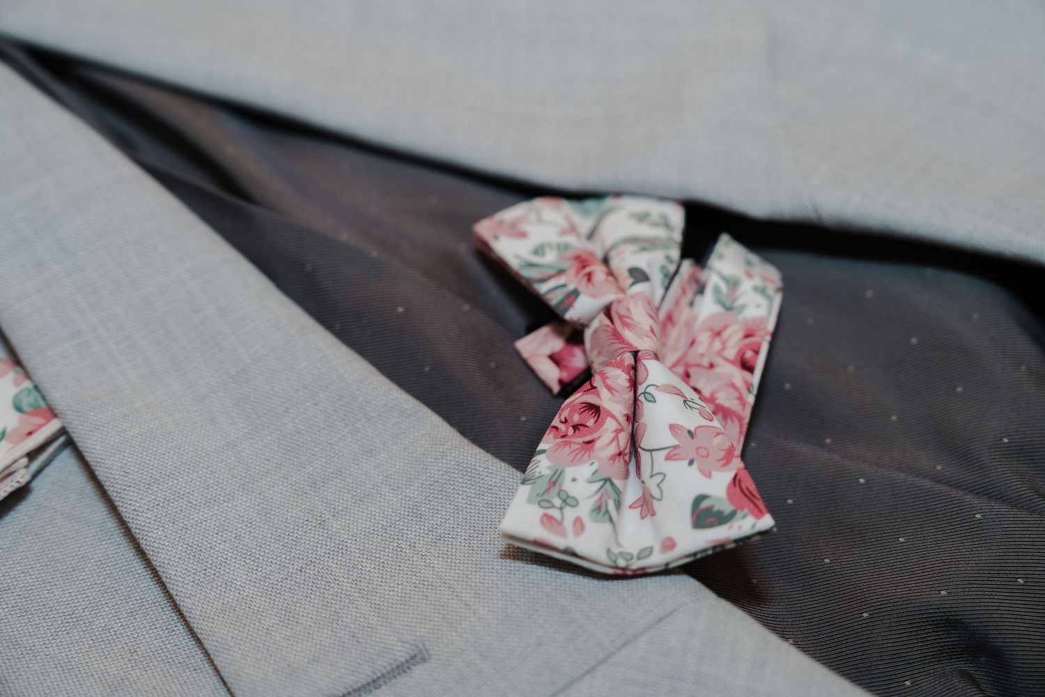 Floral print bow tie rests on light grey fabric surface.