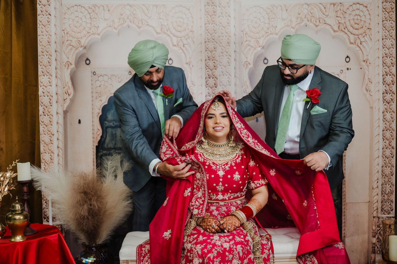 Wedding ceremony moment with attendants adjusting bride's traditional red dress.