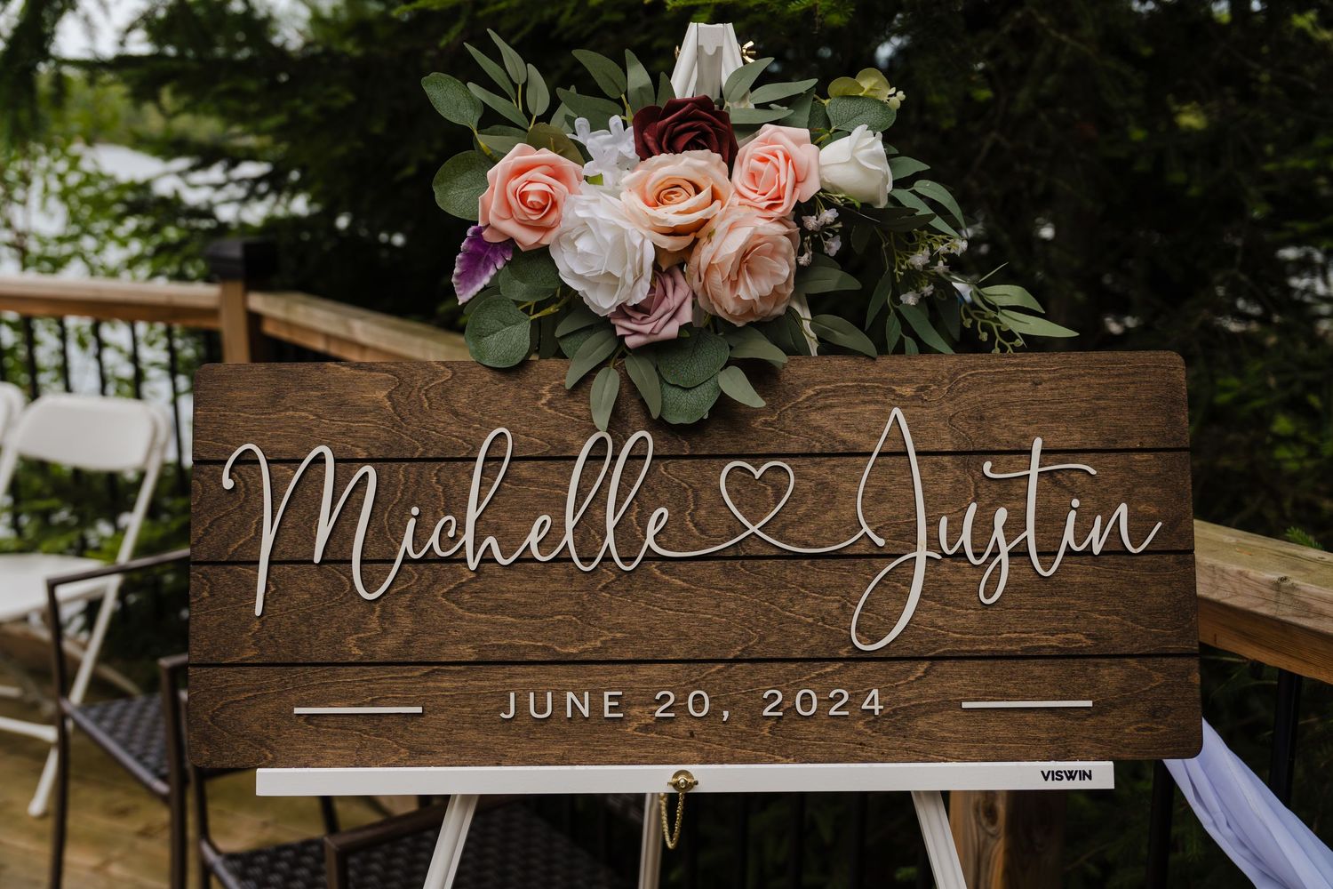 Rustic wooden wedding sign with floral decorations displaying names and date of June 20, 2024.