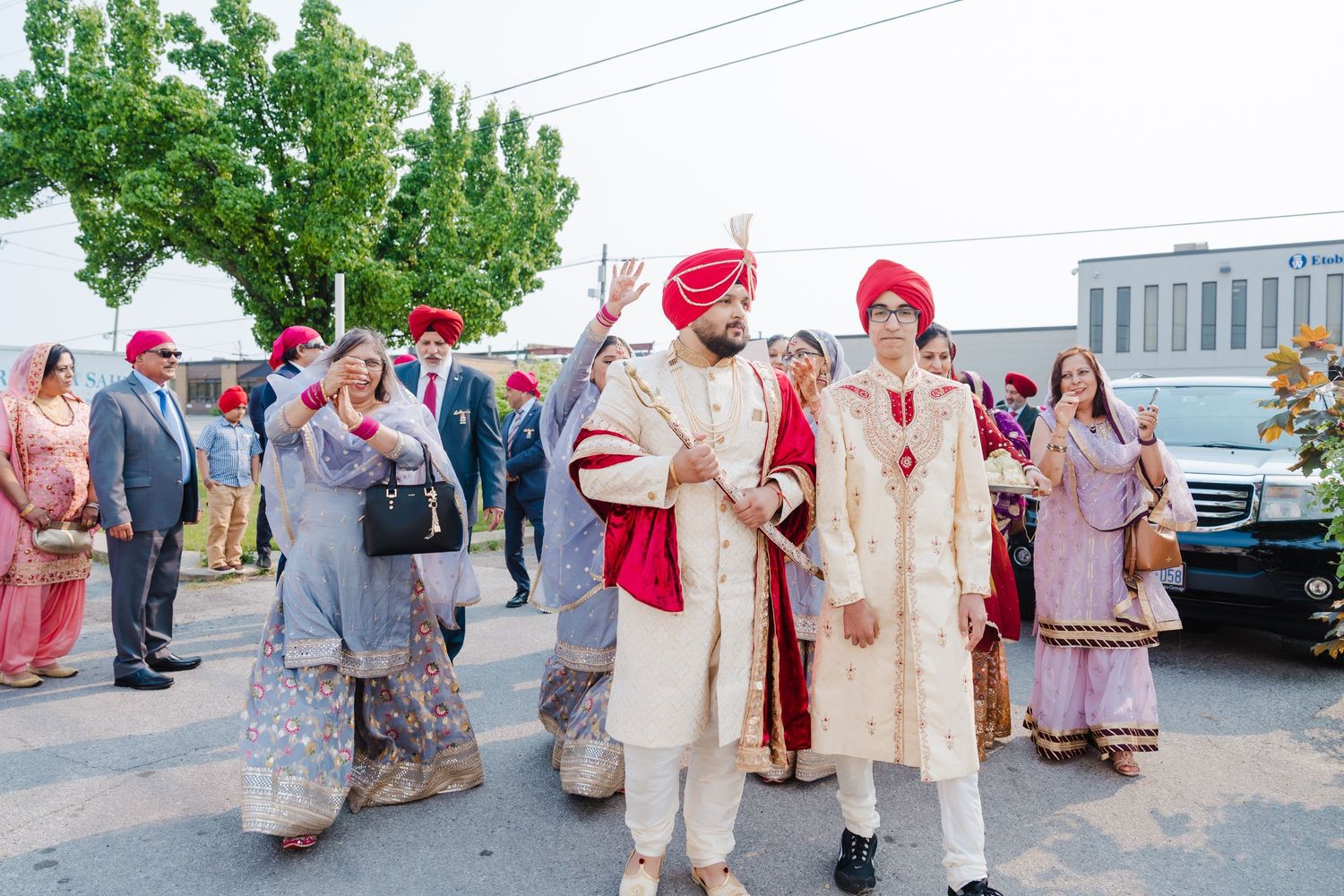 Wedding procession outdoors with participants in traditional Sikh ceremonial dress.