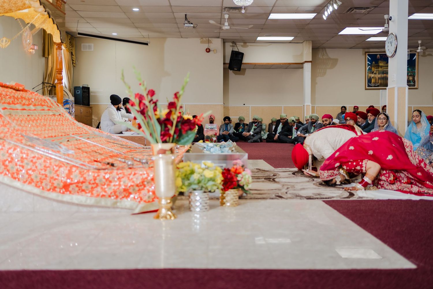 Colorful traditional wedding decorations and flowers arranged on the floor of a temple during a ceremony.