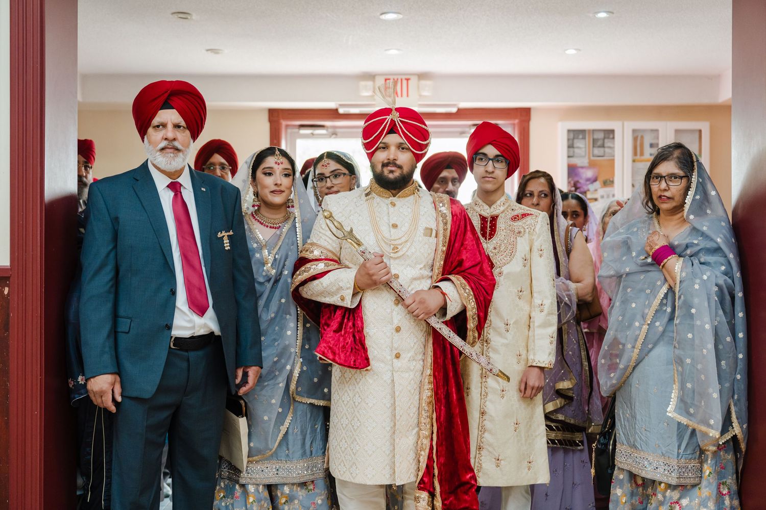 A wedding party in traditional Sikh attire poses together during a ceremony.