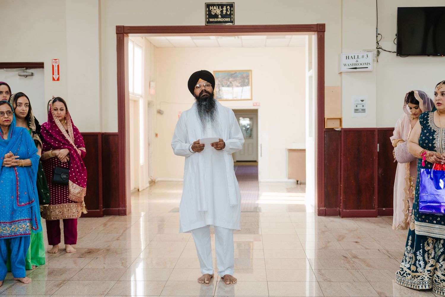 A person in white traditional Indian clothing stands in a hallway doorframe.