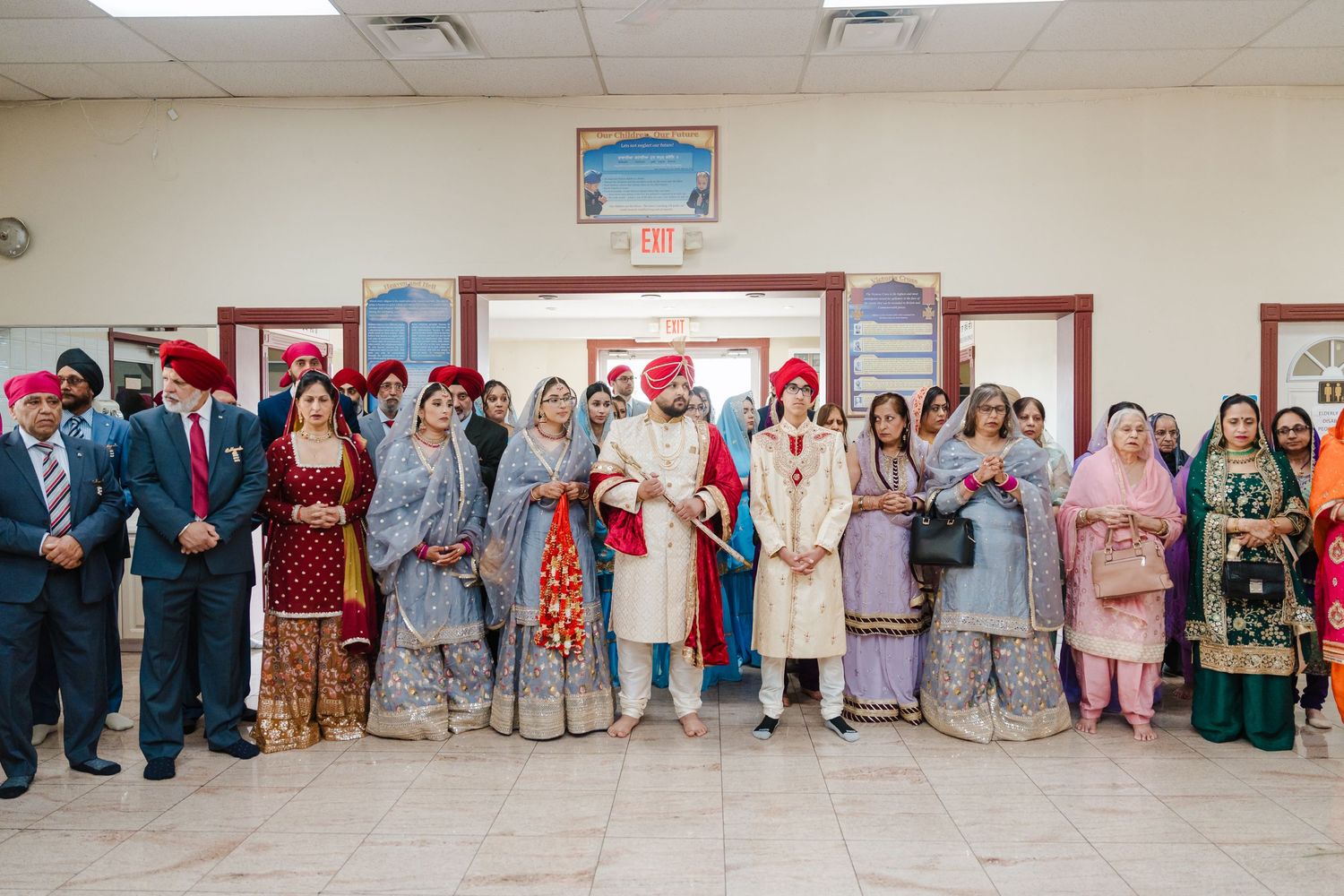 Large group of people in traditional South Asian attire gathered at a community center event.