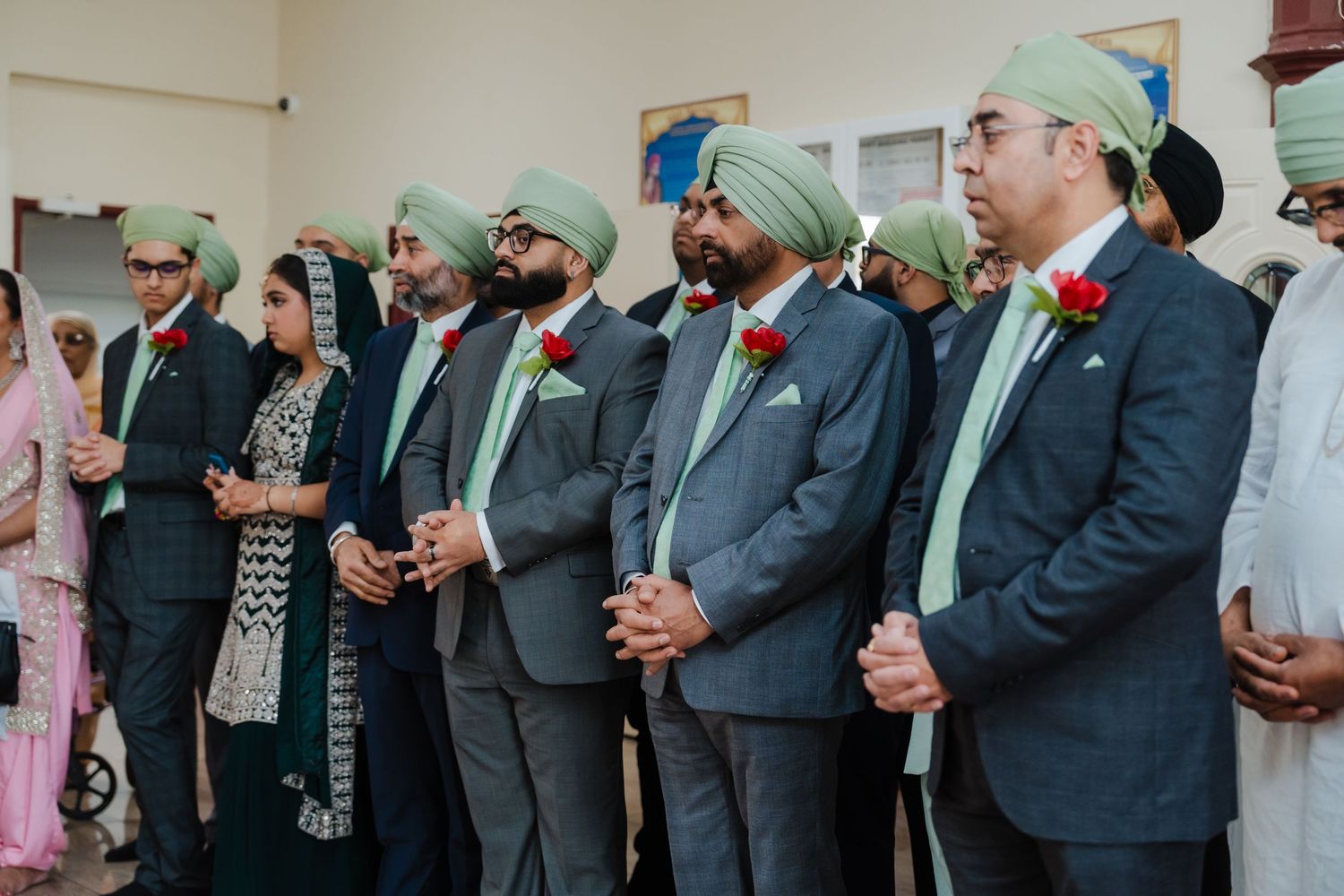 Wedding party members wearing matching grey suits and mint green turbans standing in formal lineup.