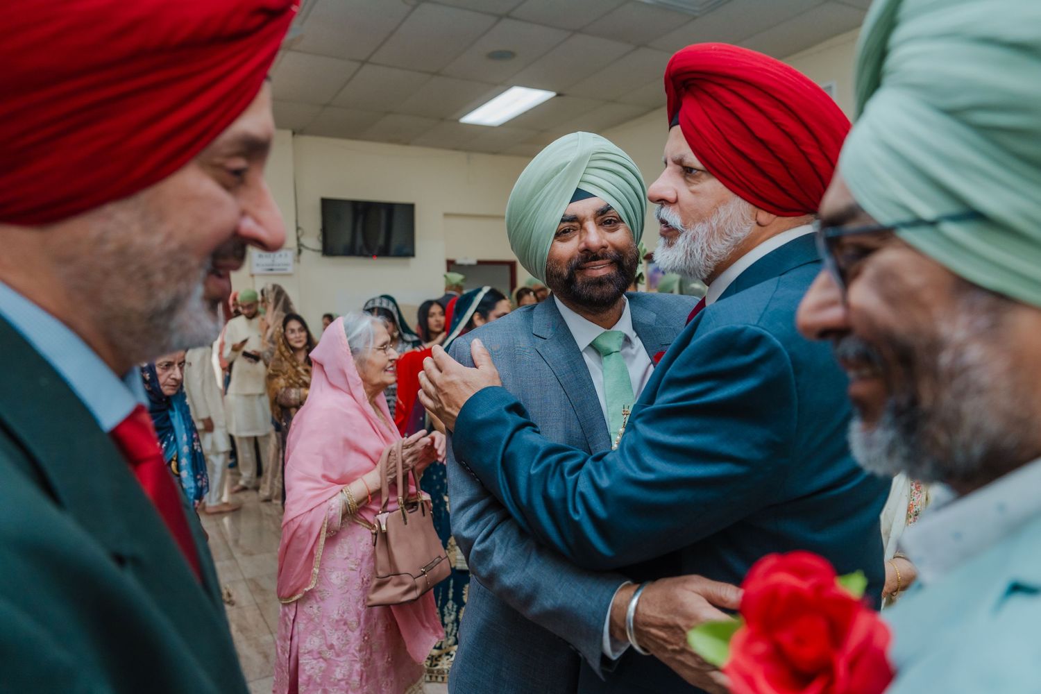 Guests in traditional Sikh attire with colorful turbans gather during a festive celebration.