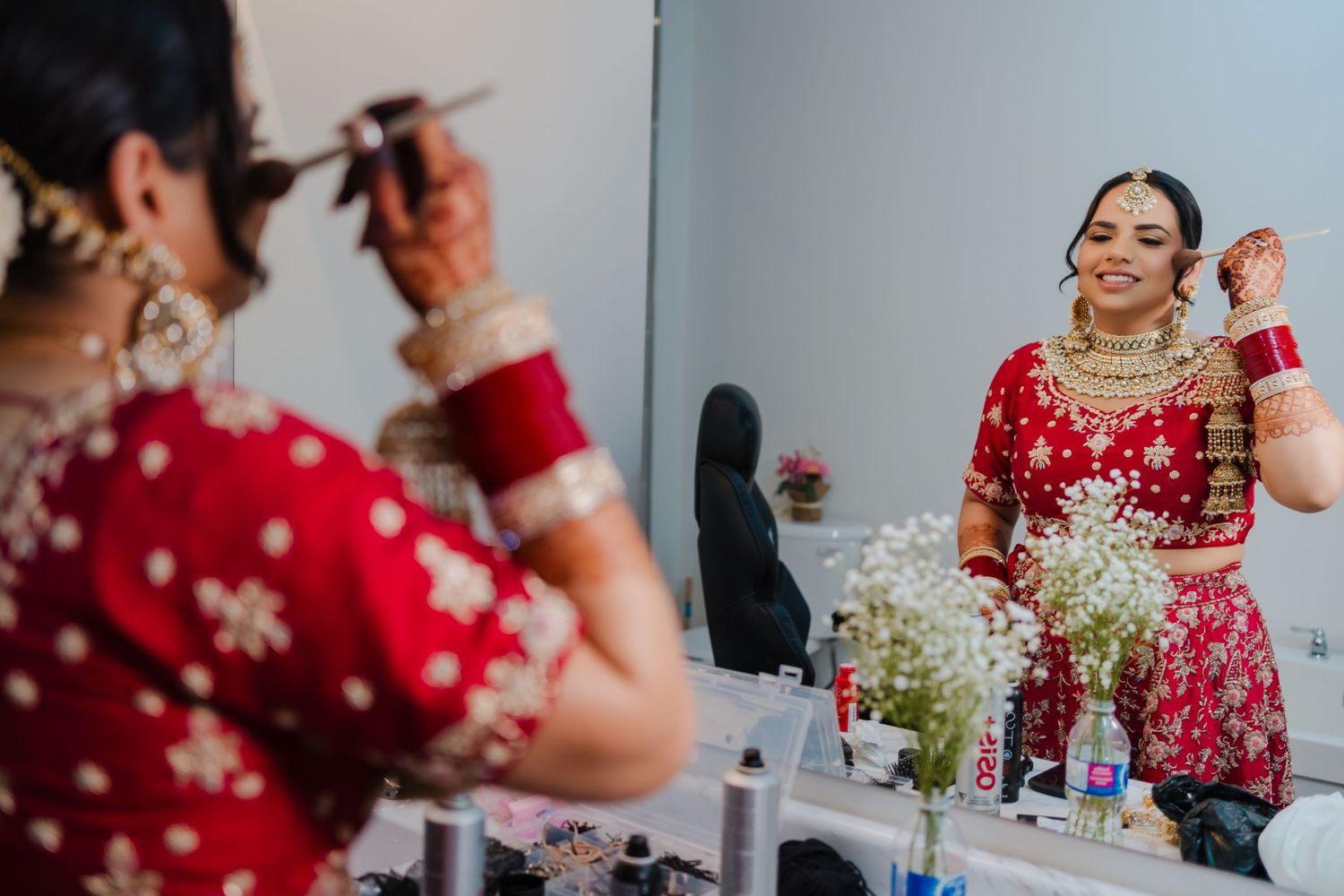 A glimpse of final wedding preparations with reflections in a mirror showing traditional Indian bridal attire.