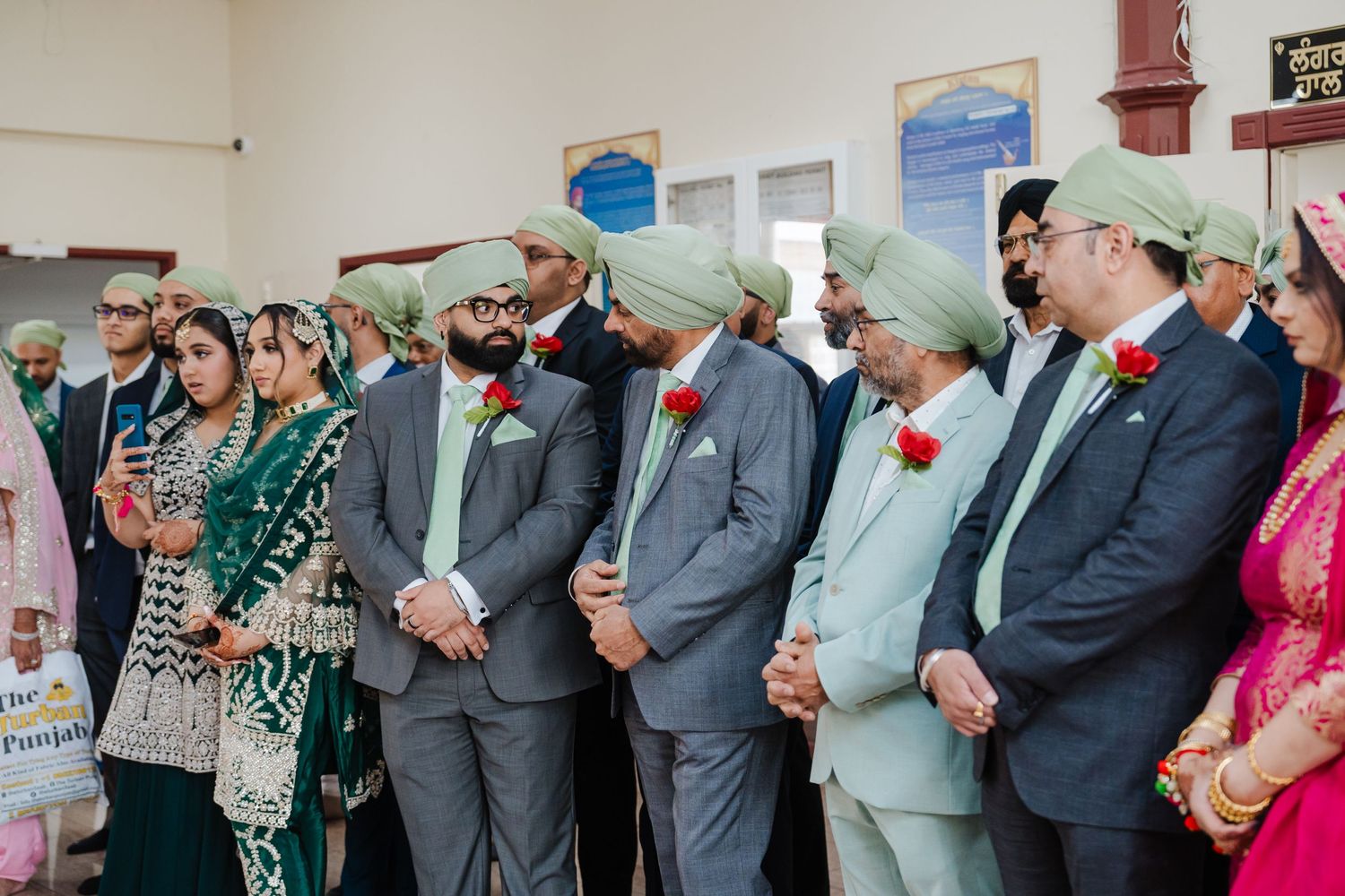 A group of wedding guests wearing formal attire stand together during a traditional cultural celebration ceremony.