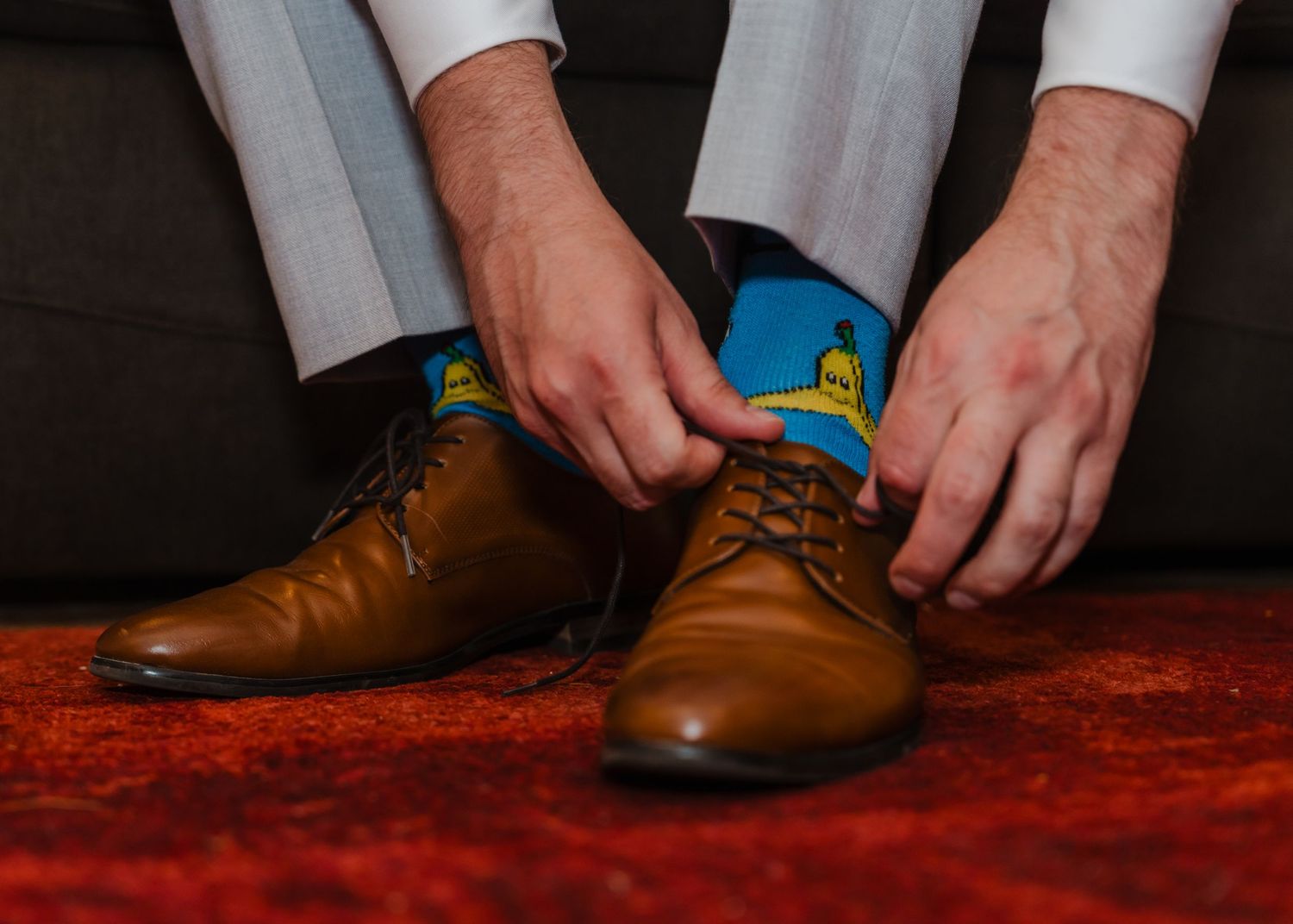 Close-up of brown leather dress shoes with blue patterned socks.