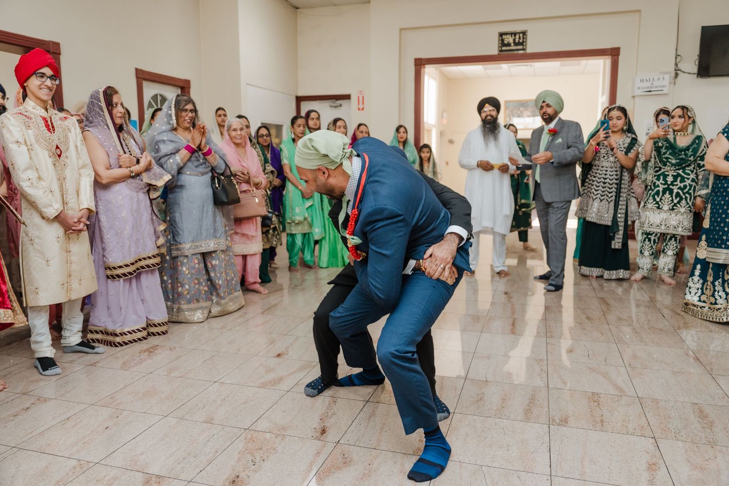 Wedding guests having fun dancing and celebrating at indoor reception venue.