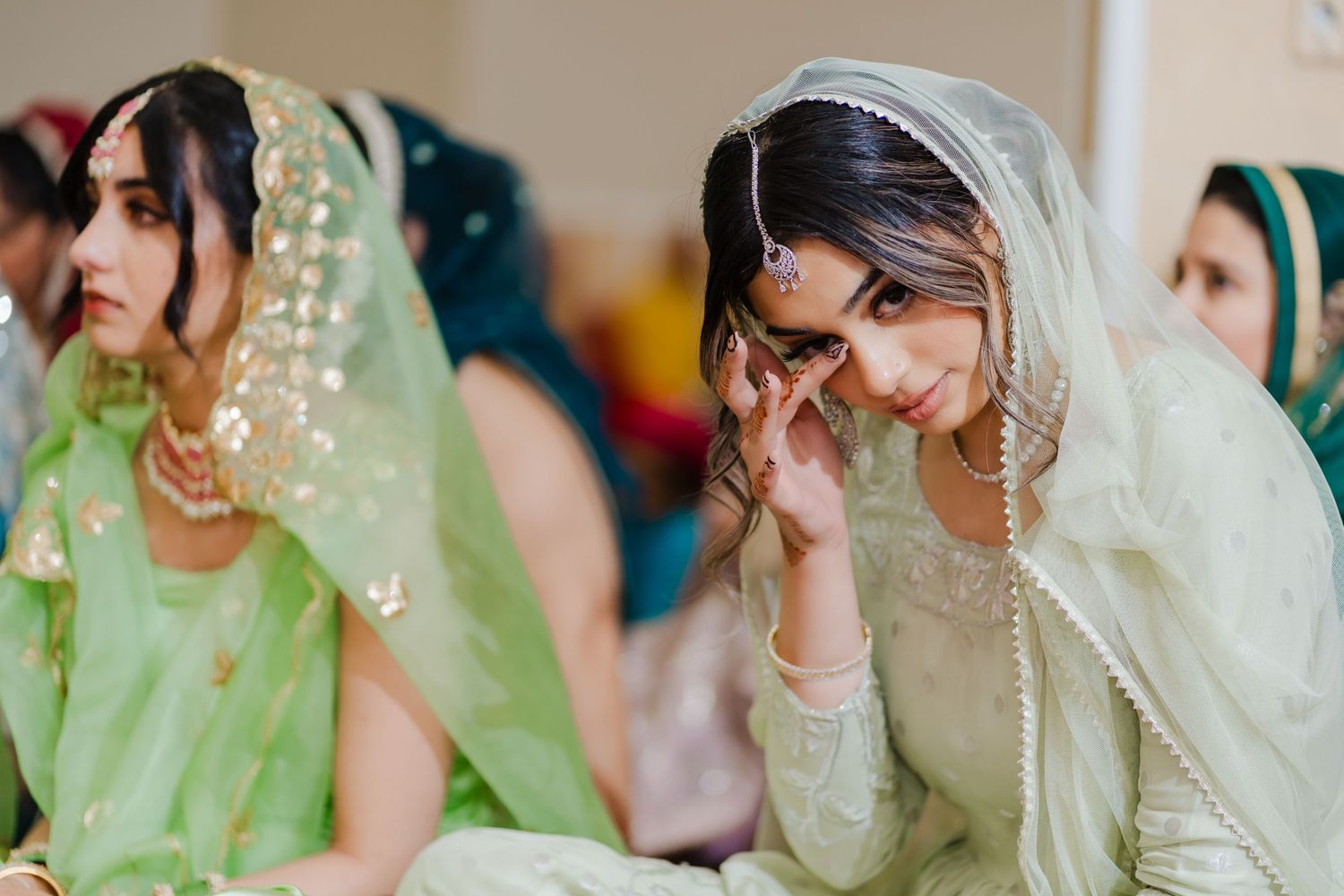 Women in traditional South Asian attire with veils and jewelry at a wedding celebration.