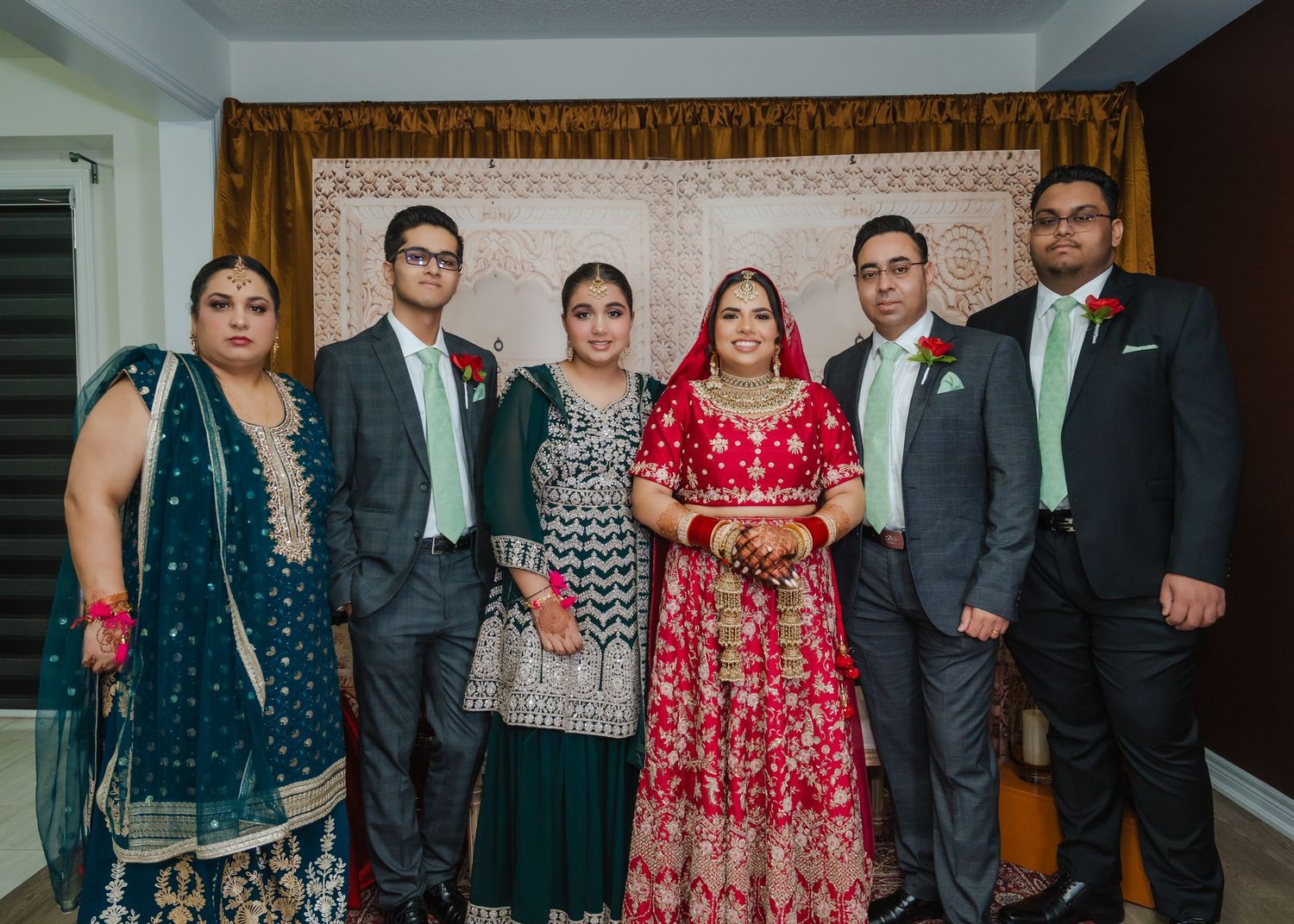 Formal group portrait of wedding party members in mix of traditional and western attire.