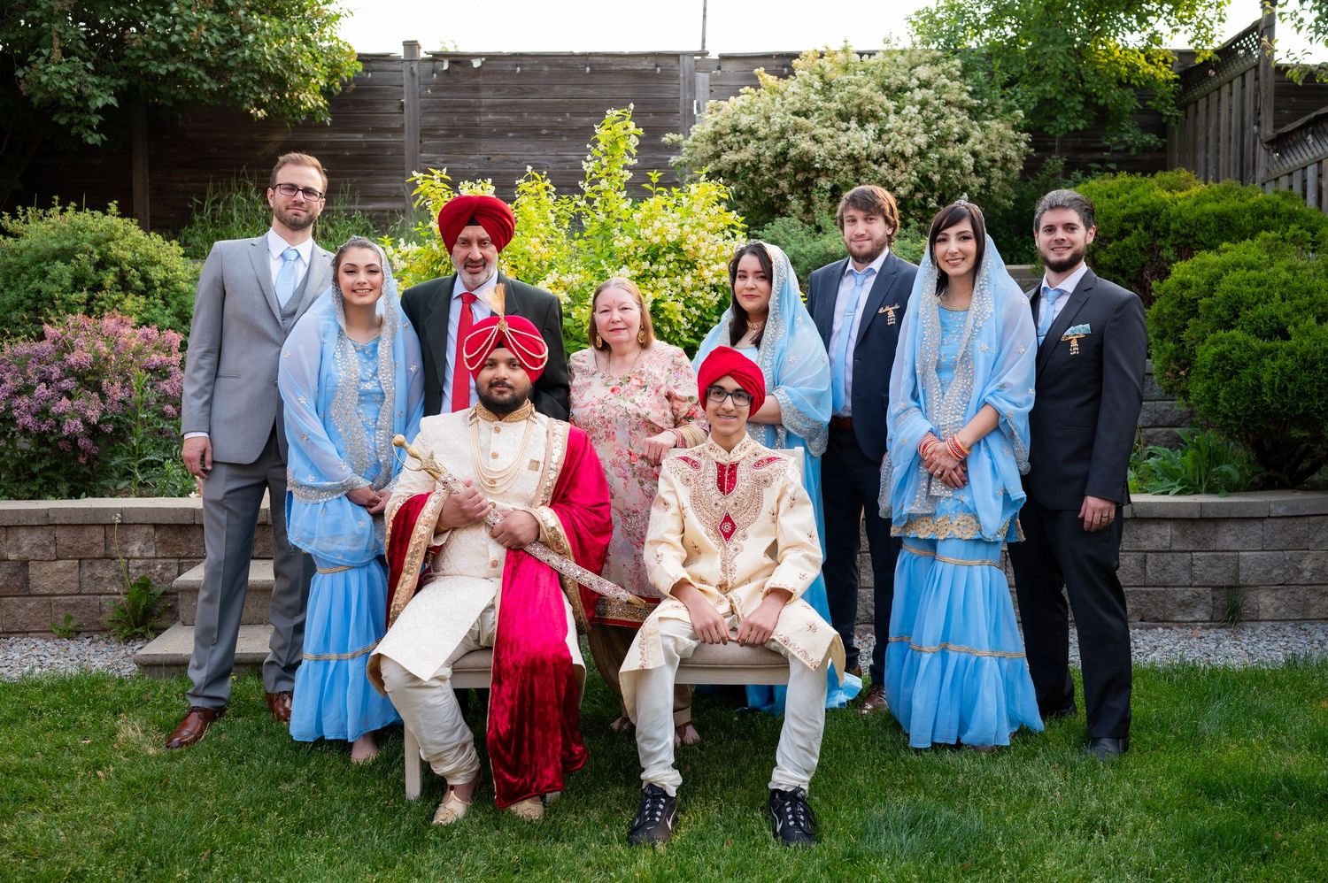 Wedding party group photo outdoors featuring mix of traditional and western formal attire.
