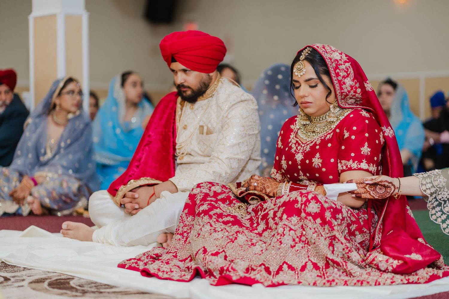 Traditional Sikh wedding ceremony with couple sitting in formal attire during religious proceedings at the Gurdwara.