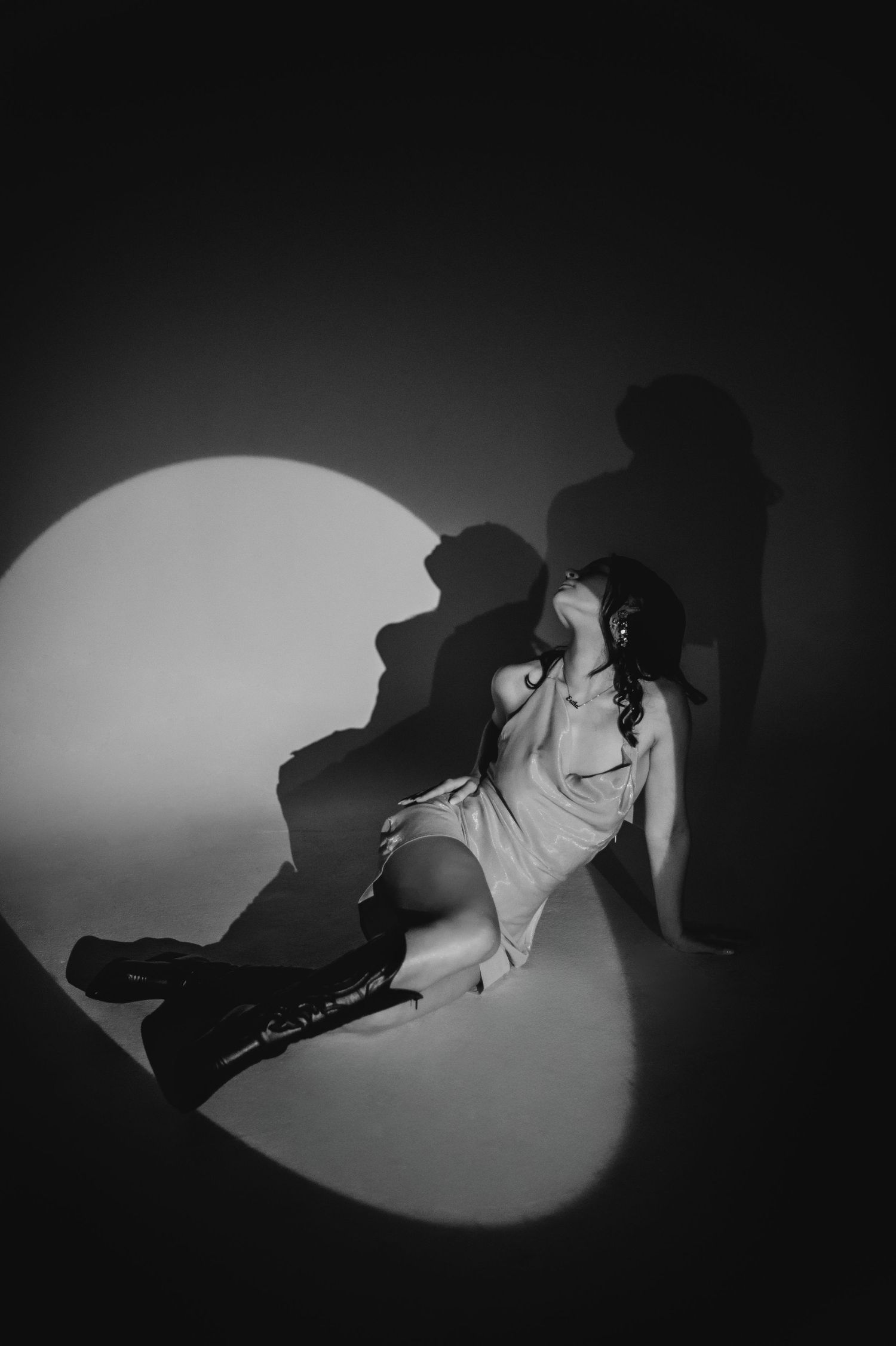 Dramatic black and white spotlight series showing silhouettes on a dark floor.