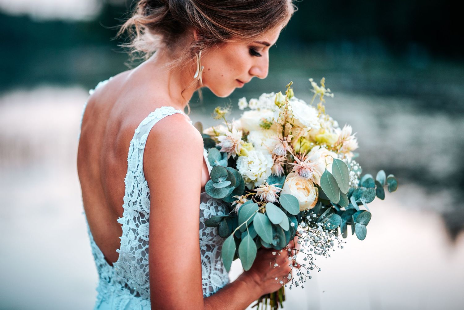 Elegant bridal portrait with soft blue tones and delicate floral bouquet.