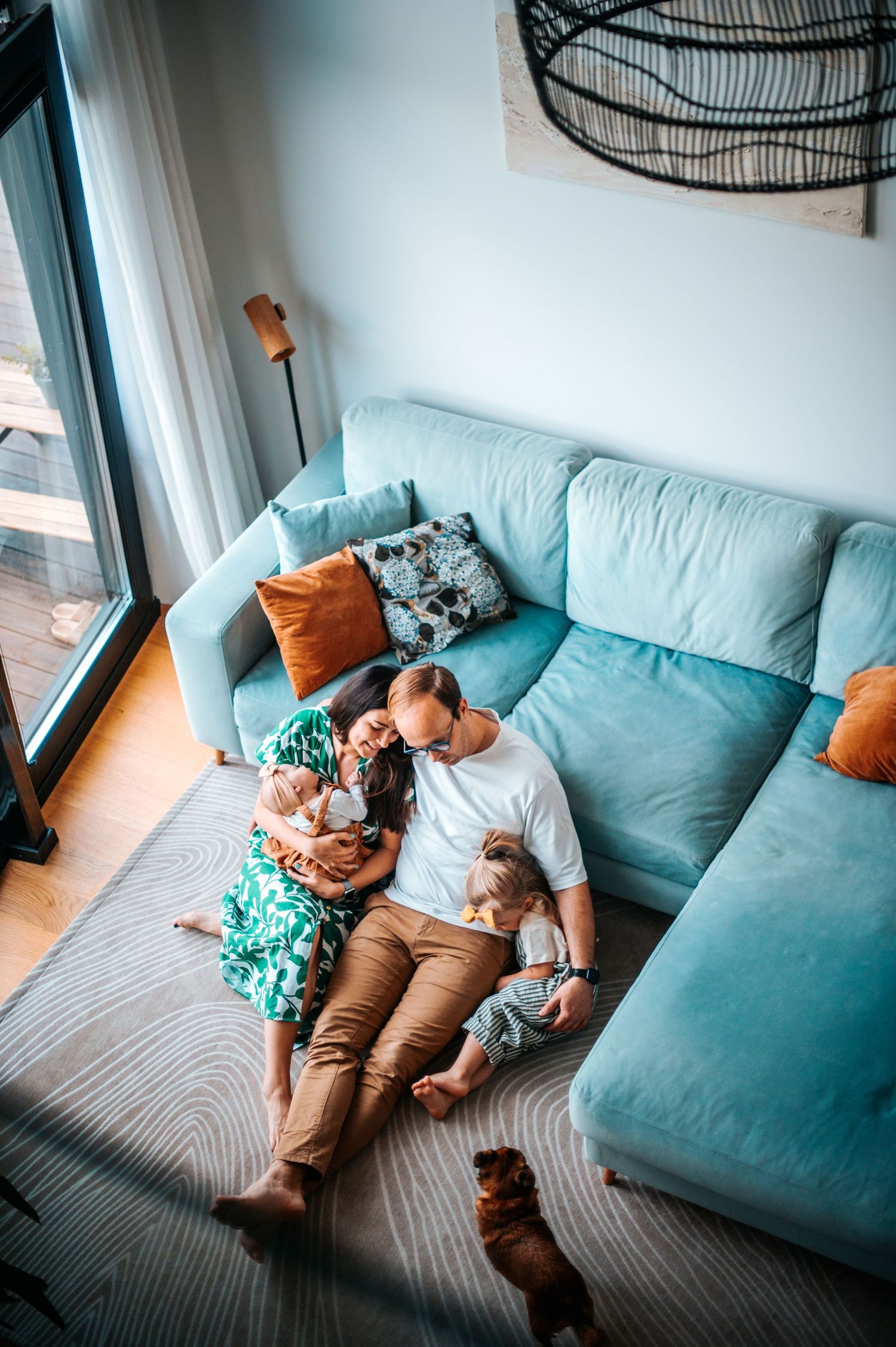 A family relaxes together on a light blue sectional sofa in a modern living room setting.
