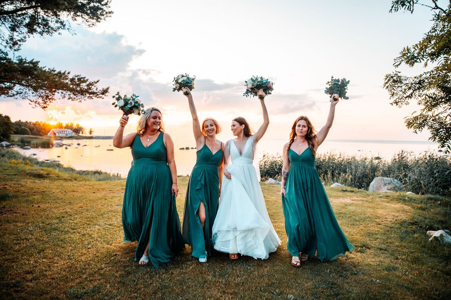 Wedding party in teal dresses celebrating outdoors at sunset.