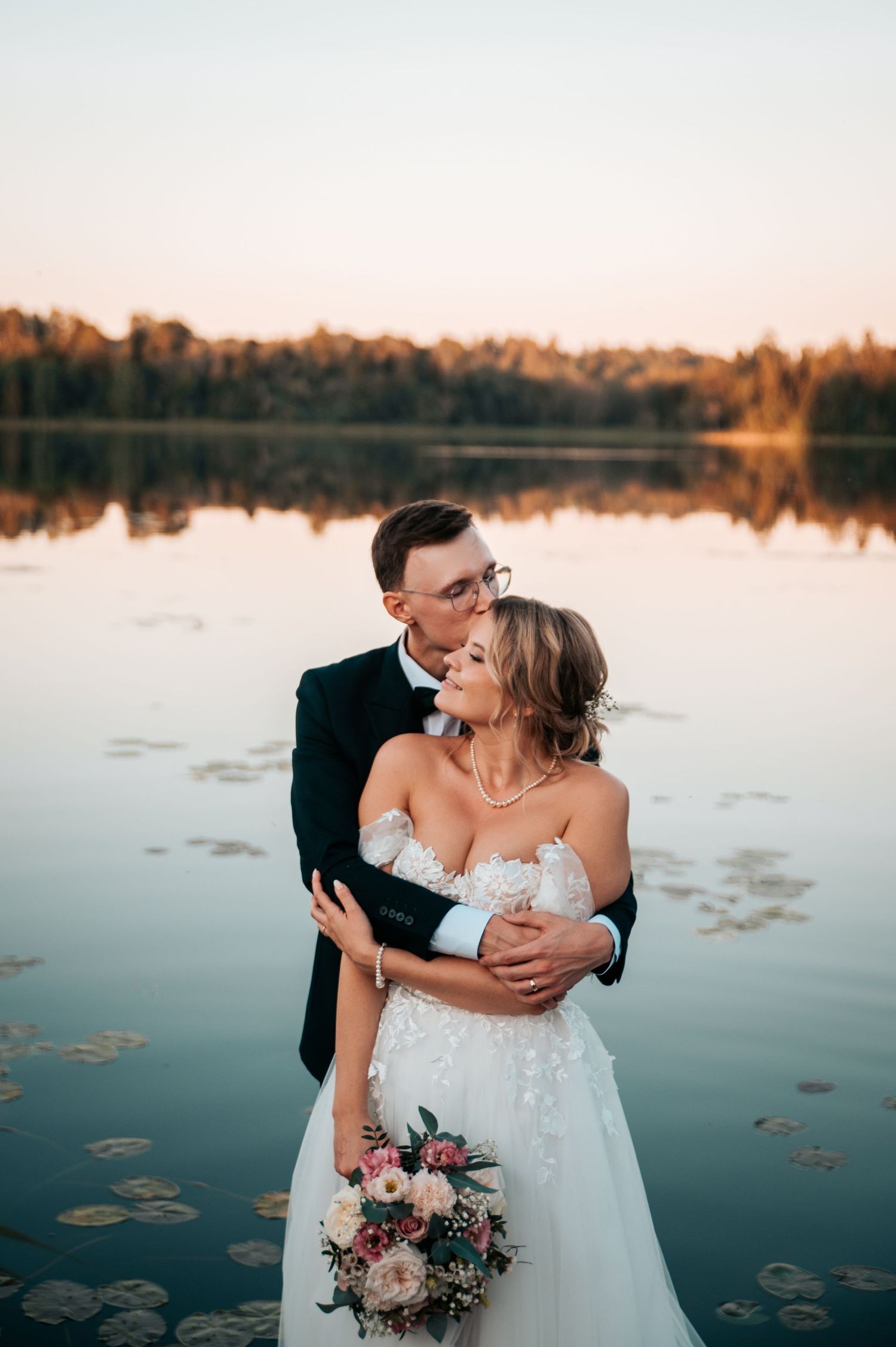 Intimate lakeside wedding portrait with couple embracing at golden hour.
