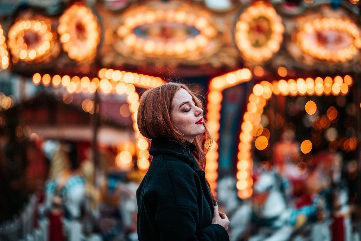 Dreamy portrait with bokeh carnival lights and warm evening glow in background.