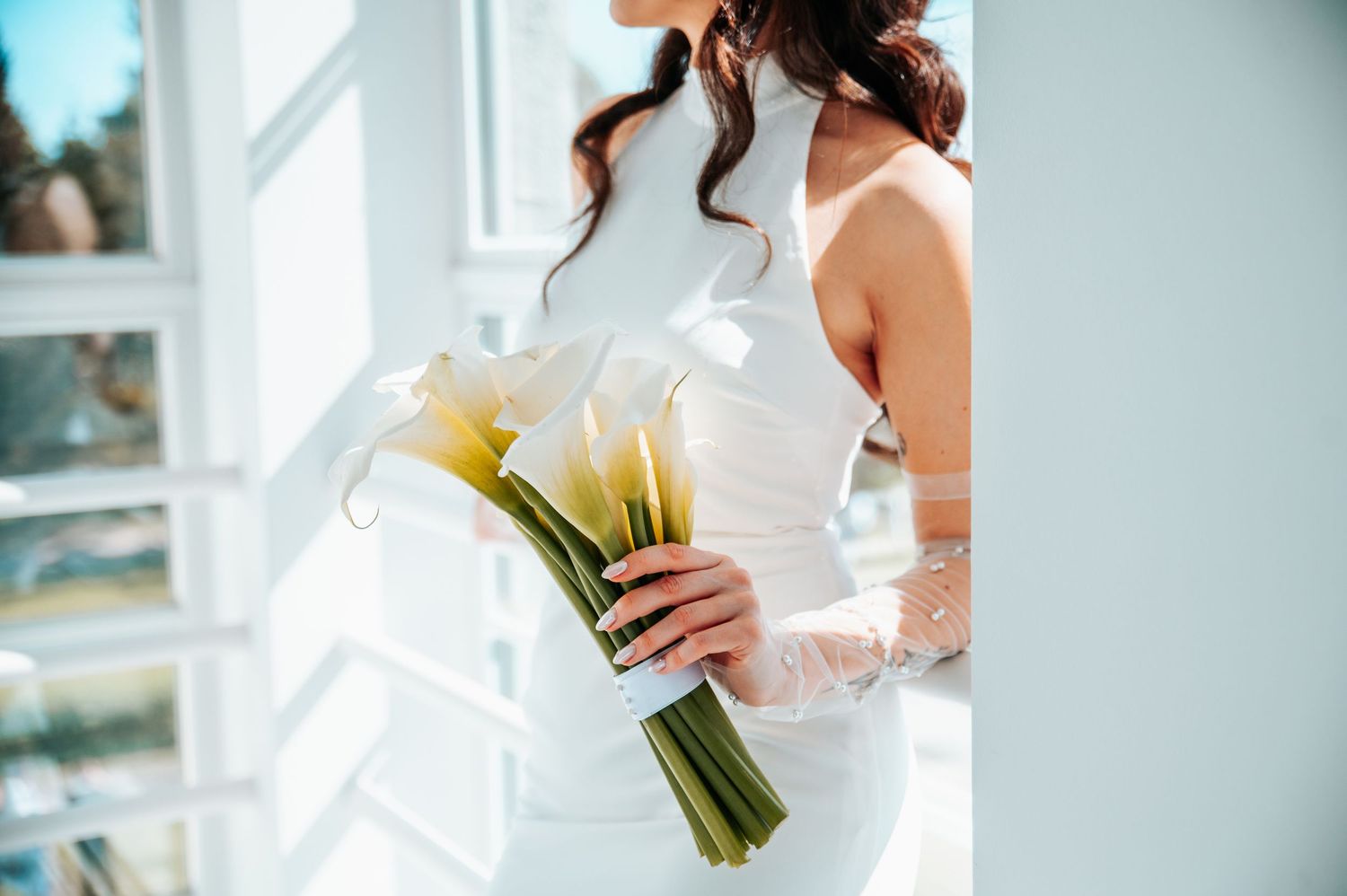 Elegant wedding details featuring a white bridal gown and bouquet against a light background.