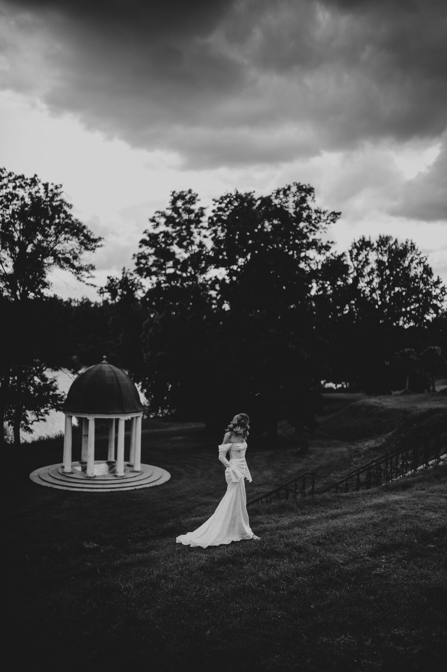 A dramatic black and white landscape photo of a garden wedding venue with a gazebo and rolling hills.
