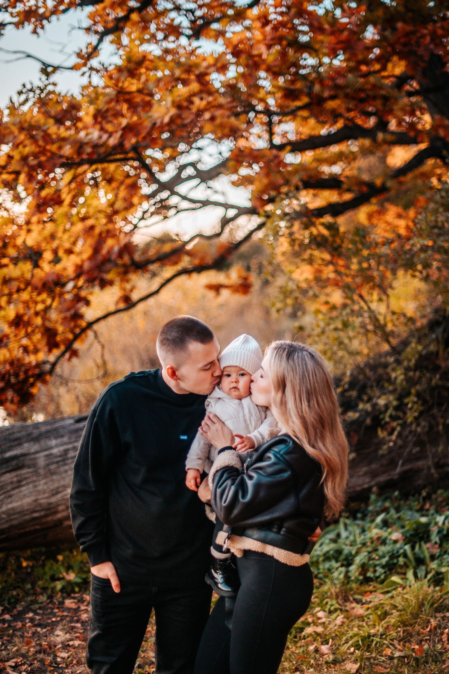A loving family shares tender moments together under vibrant autumn foliage during a fall photo session.
