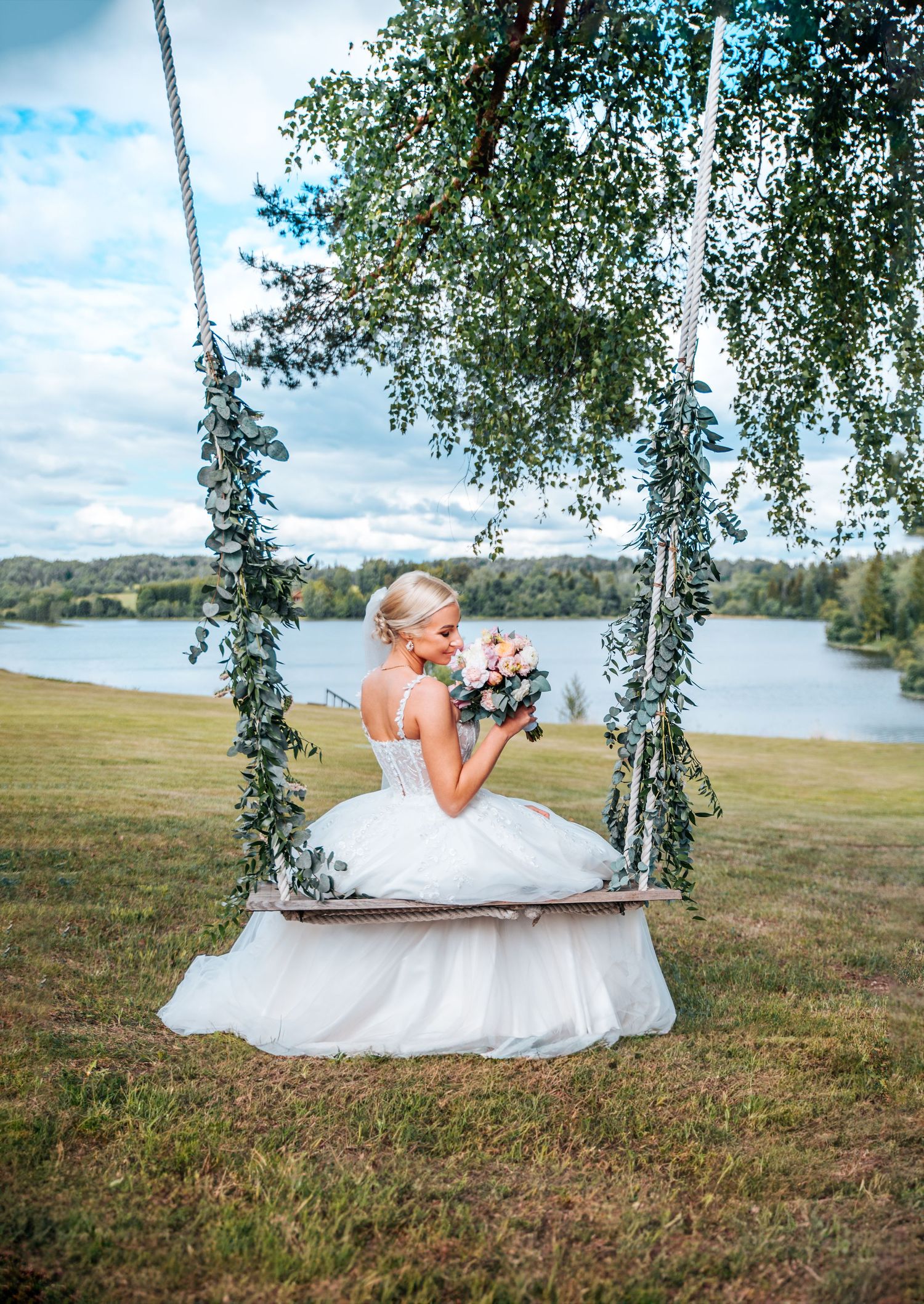 A dreamy wedding scene featuring a swing overlooking a serene lake landscape.