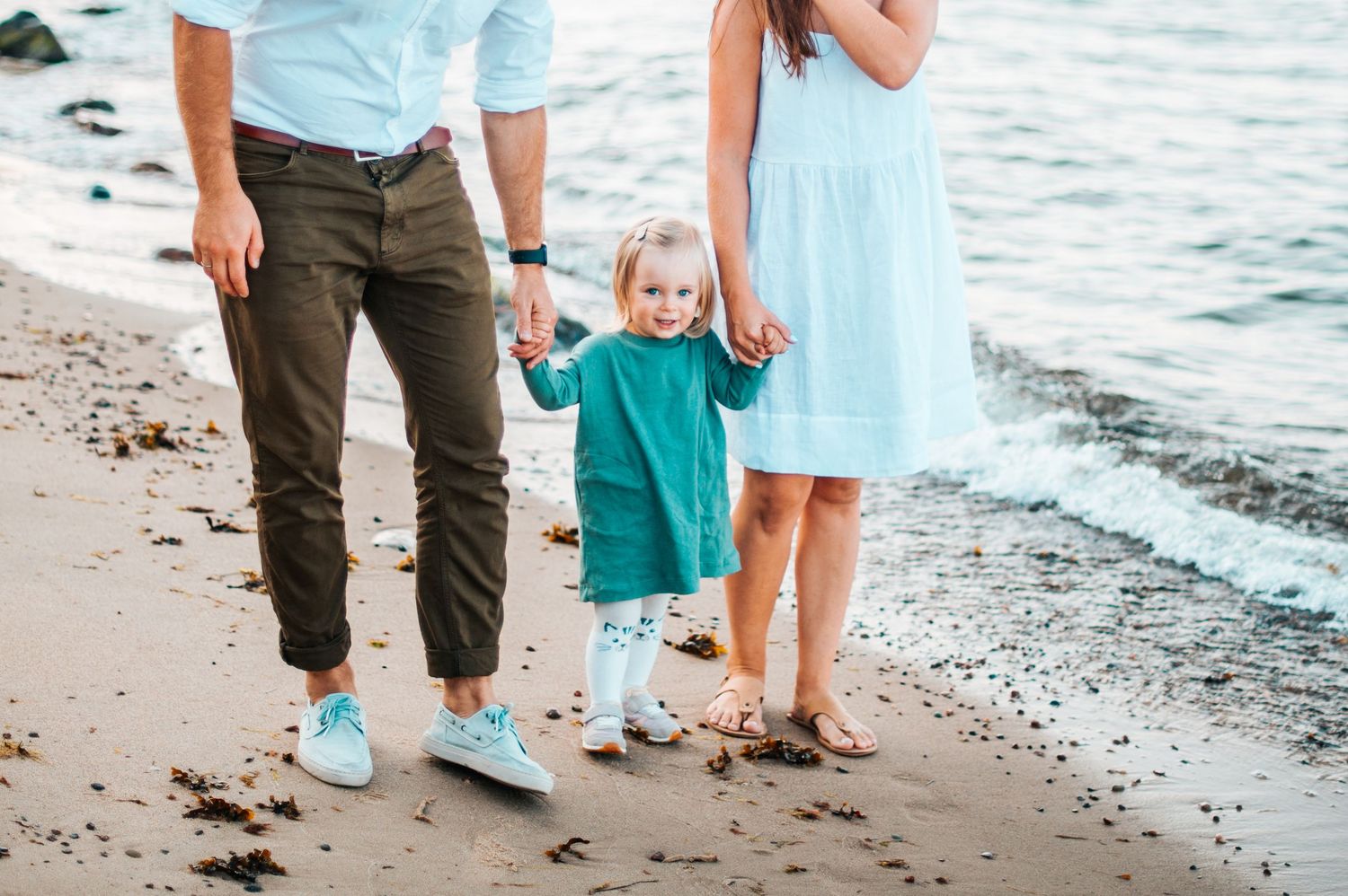 Family walking along beach shoreline with waves and sand visible in four connected photos.