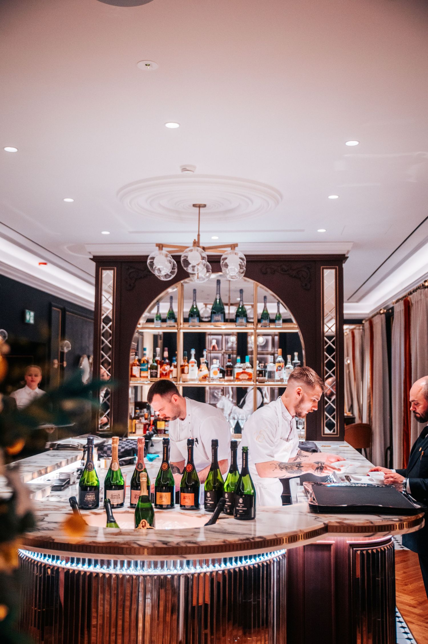 Elegant bar setup with multiple champagne bottles and crystal glassware on wooden counter.