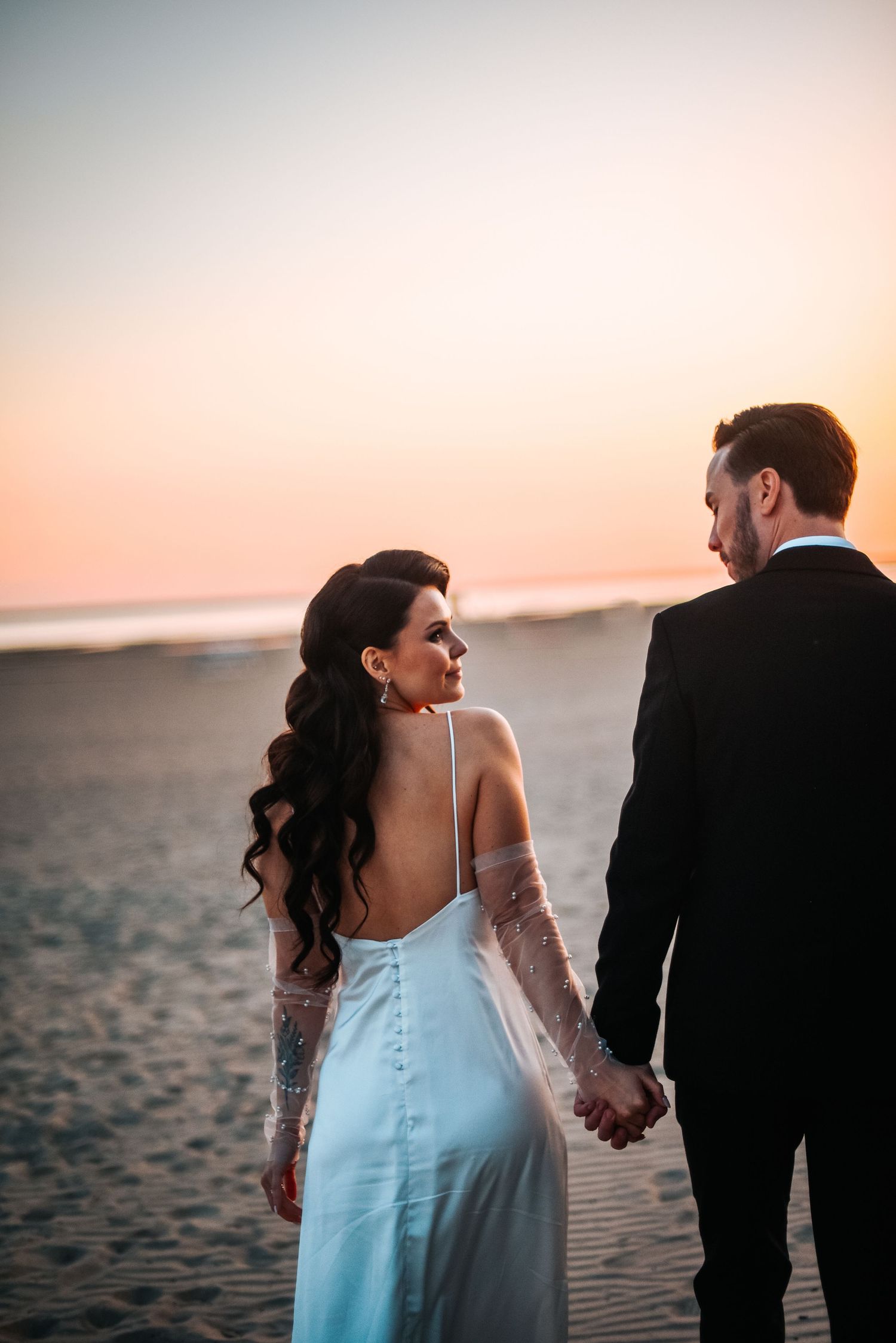 A romantic beach wedding silhouette during golden hour sunset.