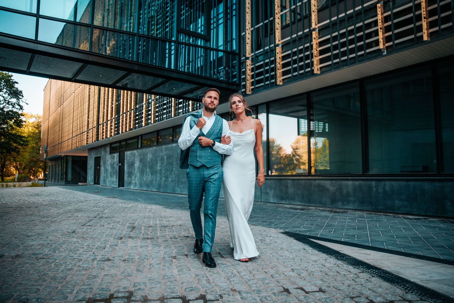 Modern architectural wedding photos with a couple walking along sleek glass buildings.