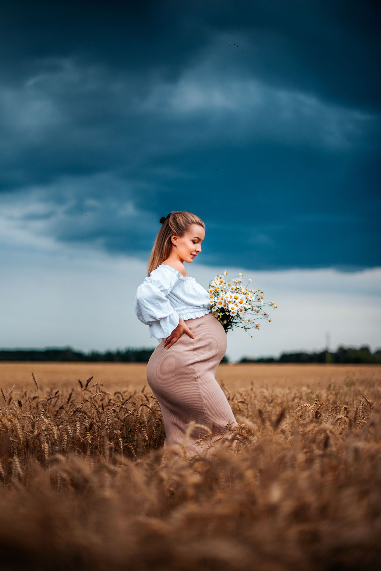 Dynamic photo sequence in a wheat field under stormy skies with flowing dress and flowers.