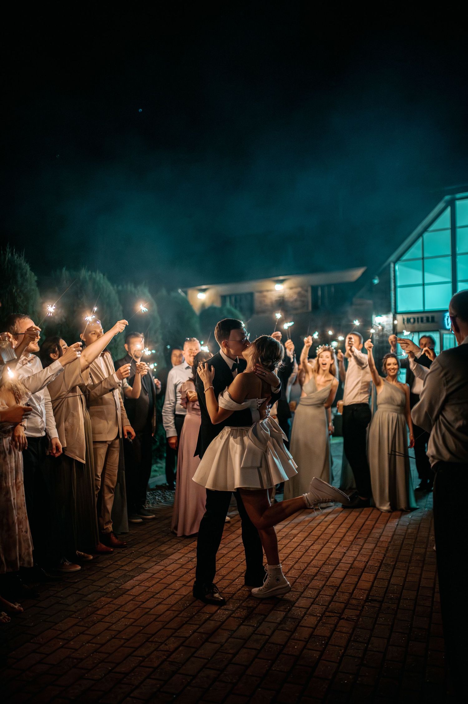 Newlyweds share first dance surrounded by sparkler-holding guests at night.