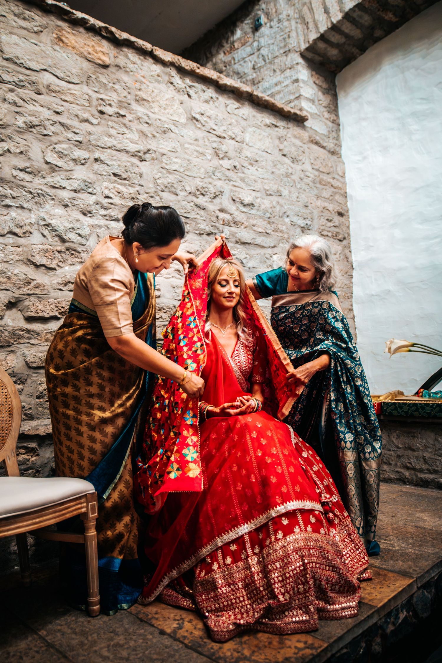 Wedding guests in colorful traditional attire celebrate in a rustic stone interior.