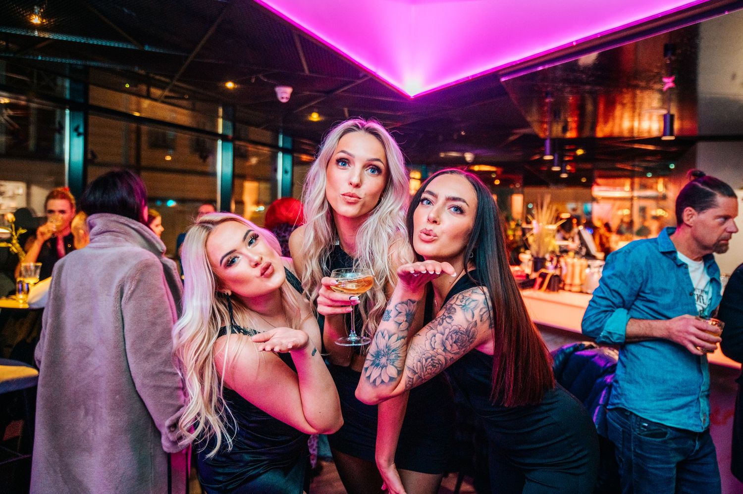 Nightclub interior with pink neon lighting and people enjoying the atmosphere.