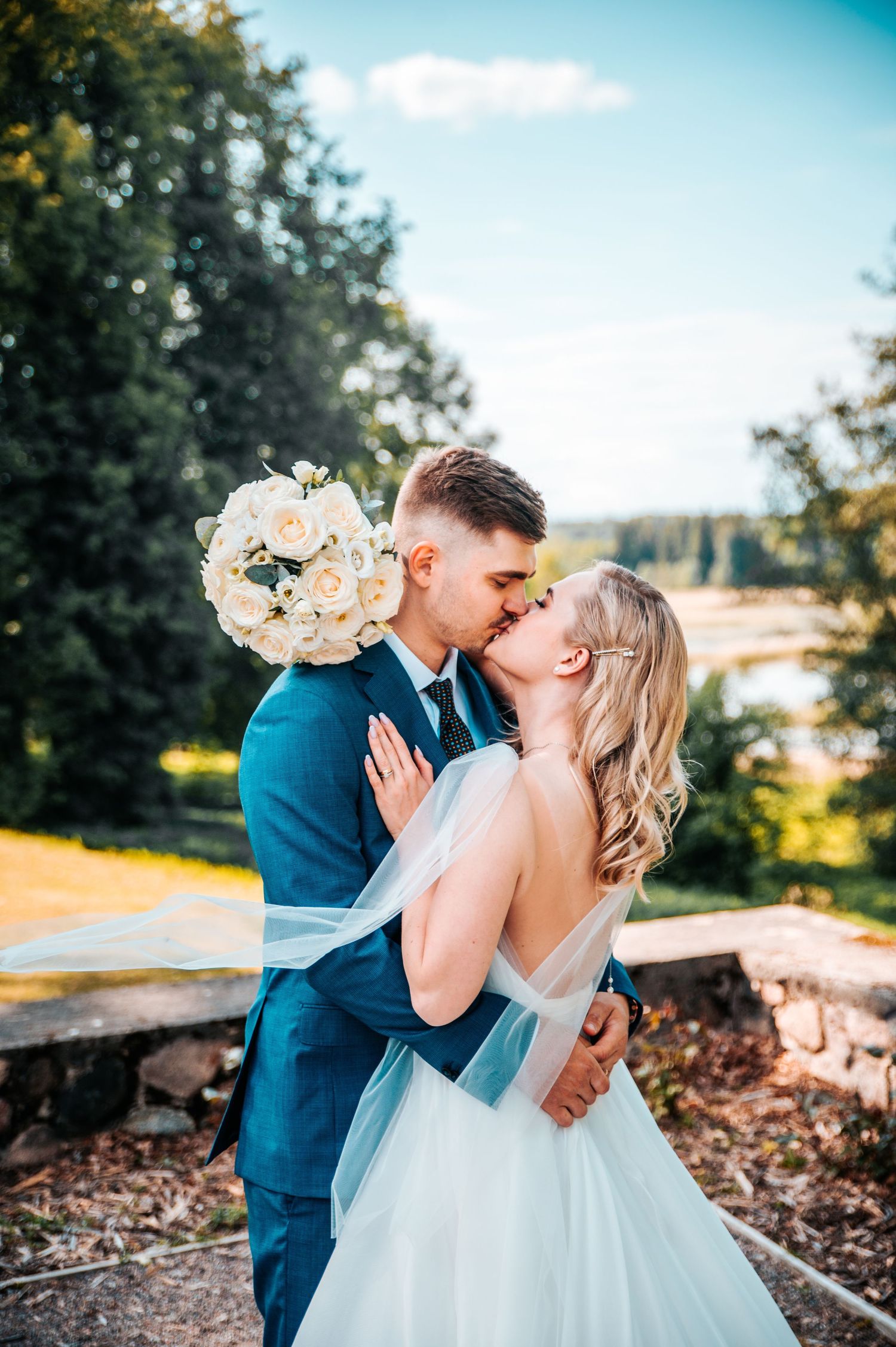 A romantic wedding moment captured in a sun-drenched outdoor setting with soft peach florals.