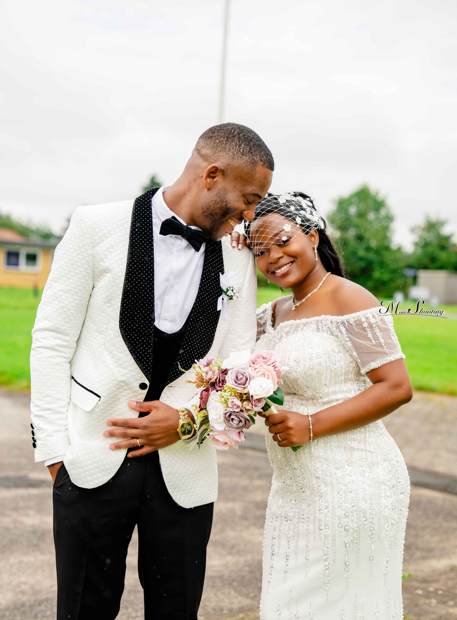 A joyful couple shares intimate moments in formal wedding attire while posing together outdoors.