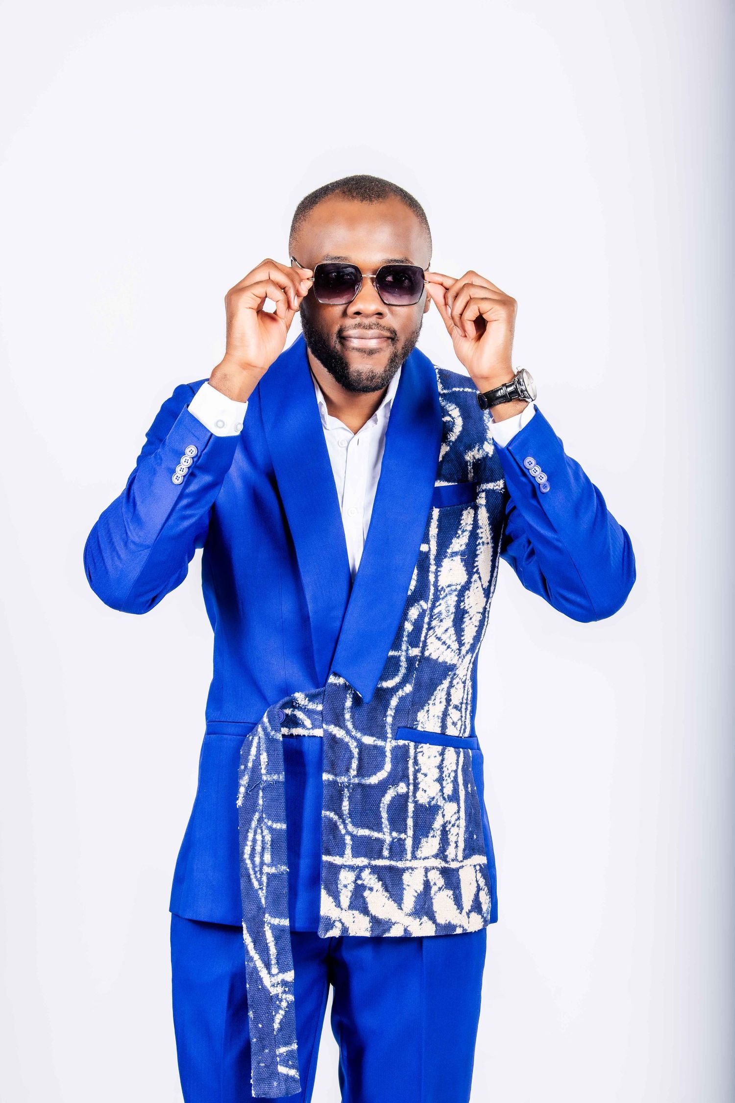 Person in bright royal blue suit with patterned vest poses confidently against white background.