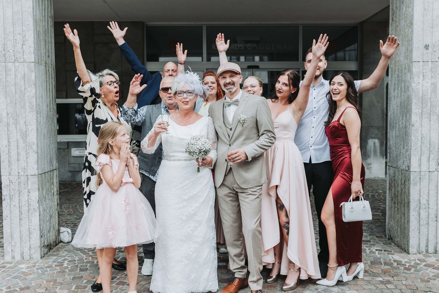 Wedding party poses together making peace signs and funny faces in a fun group photo outside a building.